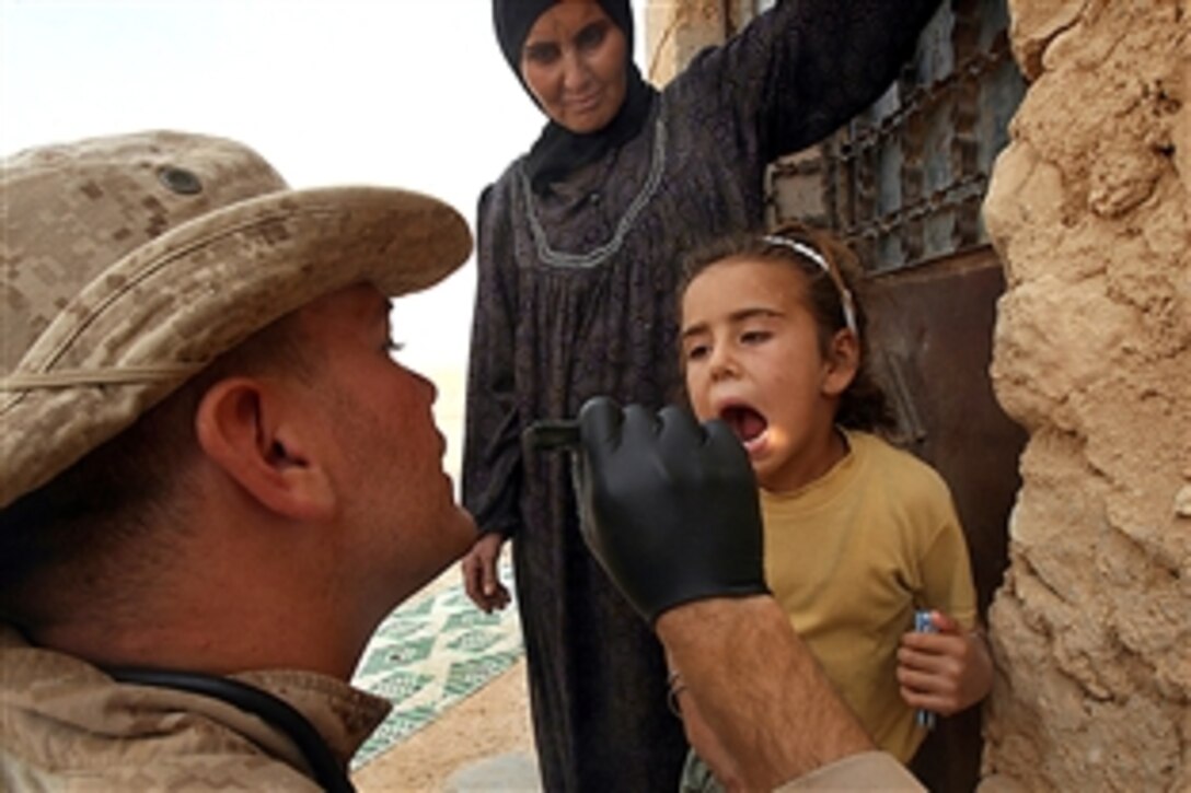 U.S. Navy Petty Officer 2nd Class John H. Holscher performs a dental exam on an Iraqi girl in Border Fort, Nine, Iraq, Oct. 24, 2008.