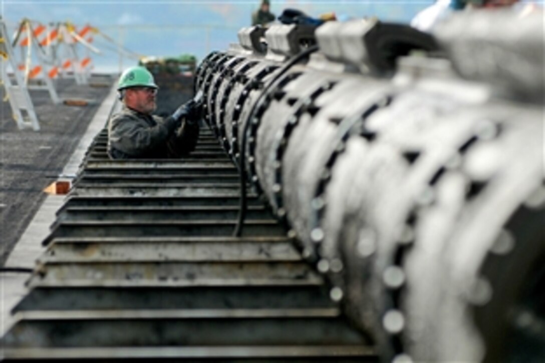 A Puget Sound Naval Shipyard worker cleans a section of a steam-powered catapult track aboard the aircraft carrier USS Abraham Lincoln, which is undergoing routine maintenance at Puget Sound Naval Shipyard, Everett, Wash., following a seven-month deployment, Oct. 30, 2008. 