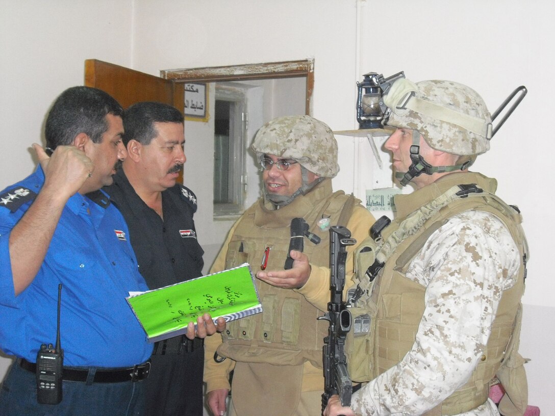 W.A. Abdulameer (second from right), an Iraqi linguist, translates a conversation between Lt. Col. Boyd Miller, the Port of Entry Transition Team (POETT) team leader, and Iraqi customs police officials at the port of entry in Trebil, Iraq, Nov. 3.  Abdulameer, who survived three deadly insurgent attacks while working as a linguist for Coalition forces in Baghdad from 2004-2007, emigrated to the U.S. more than a year ago, but volunteered to return to his native land with the POETT.::r::::n::