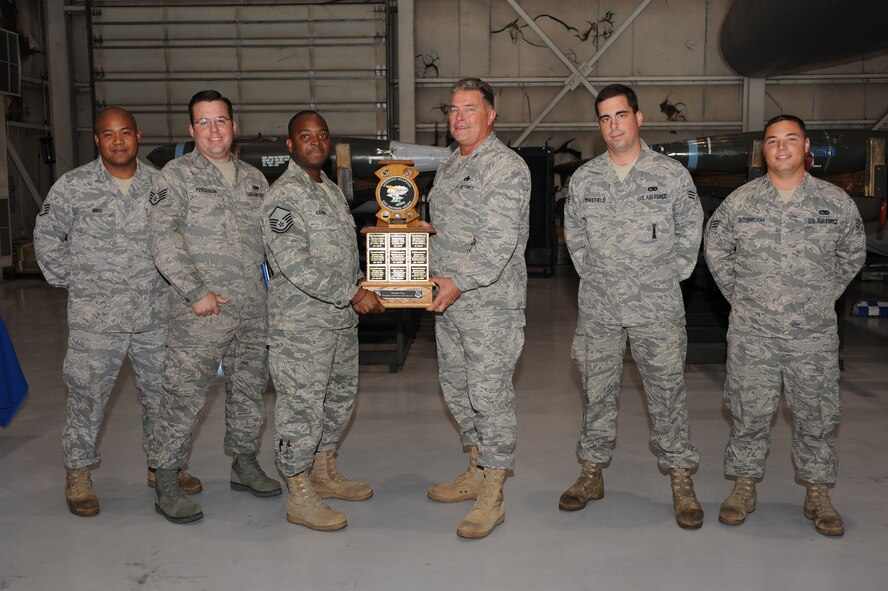 DYESS AIR FORCE BASE, Texas -- Colonel James Milburn, 7th Maintenance Group commander, presents the 7th Bomb Wing Weapons Load Crew of the Quarter Award to Staff Sgt. Teddy Miro, Staff Sgt. Blake Ferguson, Master Sgt. Michael Cook,  Senior Airman Brandon Morefield, and Senior Airman Seth Rosbrugh in the Load Training facility Oct. 24. Weapons Load Crew competitions are held quarterly. The competitions pitt crews against each other in a timed event to see who can load weapons in the most accurate, fastest and safest way. Load crews were also graded on their dress and appearance, a knowledge test and an inspection of their Composite Tool Kit. (U.S. Air Force photo/Senior Airman Courtney Richardson)