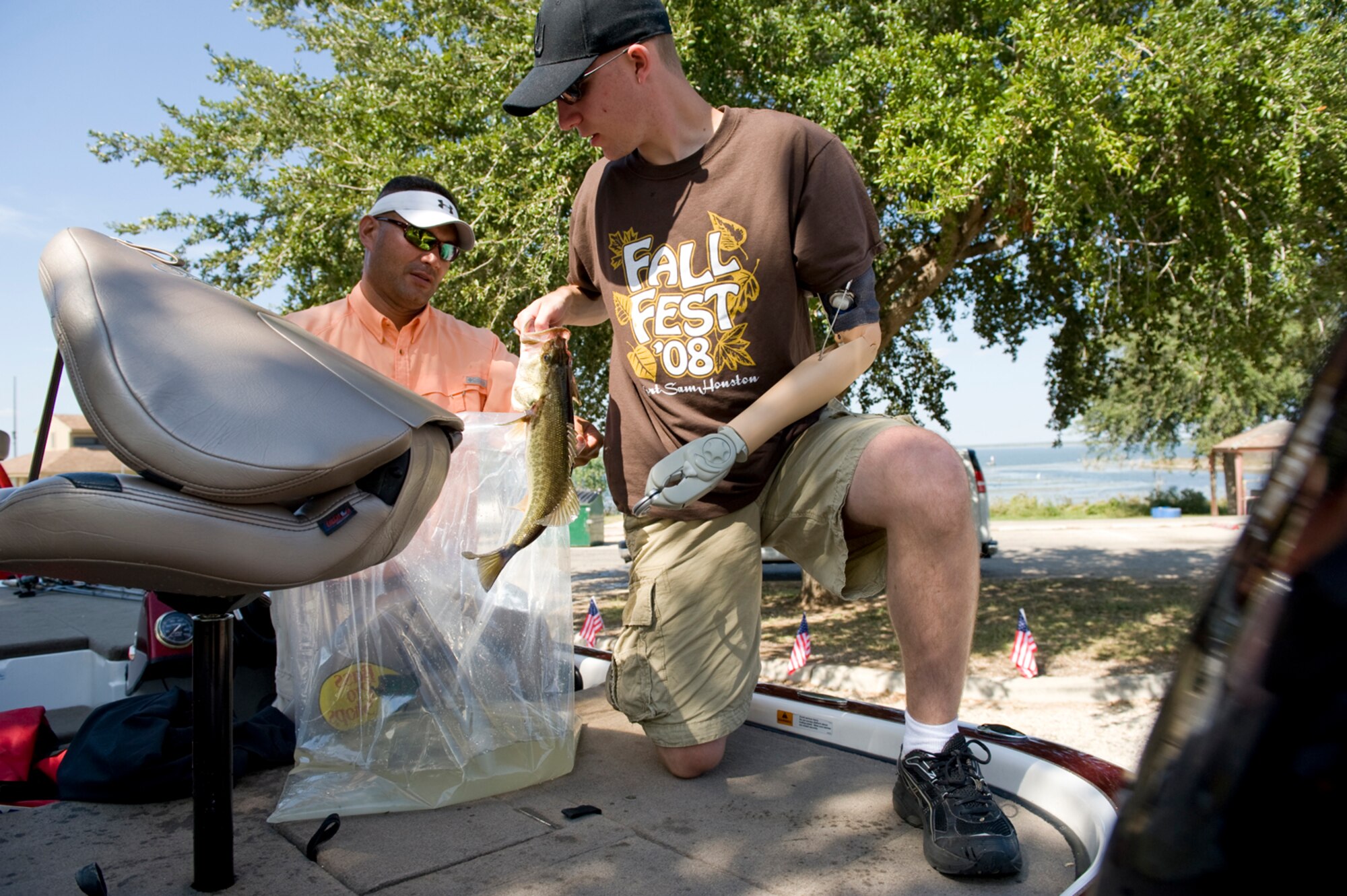 Senior Airman Marcus Creason (right) removes his largest bass of the day from the live well for weighing during Fishing for Freedom V held Oct. 25 at Choke Canyon, Texas. Airman Creason and his fishing partner Tech. Sgt Chuck Bunch (left) finished the competition with their largest fish weighing 3 pounds, 1 ounce. Thirty-three injured servicemembers participated in the event. (U.S. Air Force photo/Master Sgt. Jack Braden)
