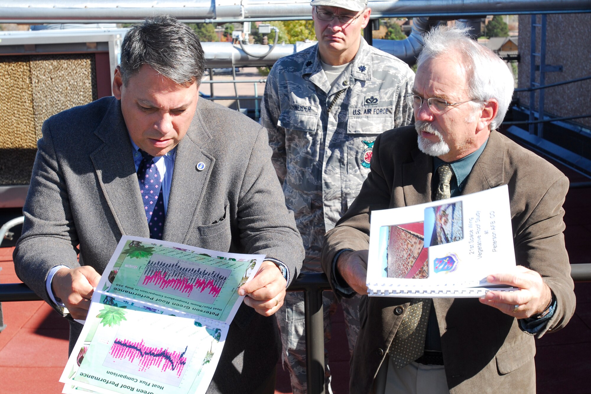 The Honorable Kevin Billings, acting assistant secretary of the Air Force for installations, environment and logistics, goes over charts of the GreenGrid roof with Randy Hawke, 21st Civil Engineer Squadron, on top of Bldg. 845 during the secretary's Oct. 28 visit to Peterson AFB . (Air Force photo/Rob Lingley)