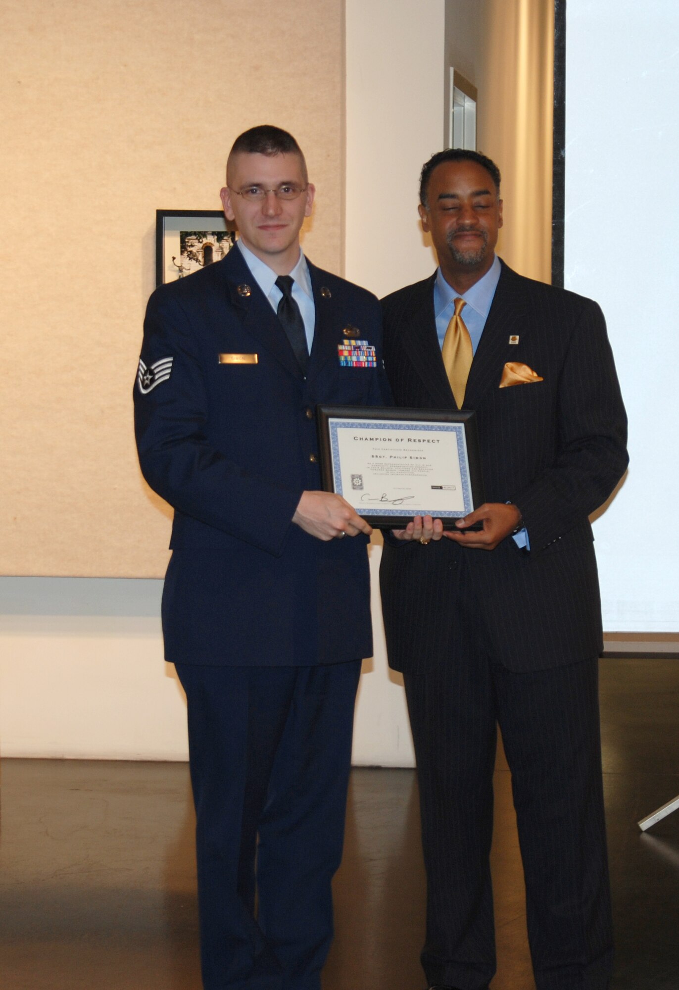 Wichita, Kan. -- Staff Sergeant Philip Simon, 22nd Operation Group, accepts recognition from Mark McCormick, Wichita Eagle columnist, for being selected as a 2008 Champions of Respect by the Wichita/Sedgwick County Domestic Violence/Sexual Assault Coalition, at the Wichita City Arts center, Oct. 30. (Photo by Airman 1st Class Jessica Lockoski)