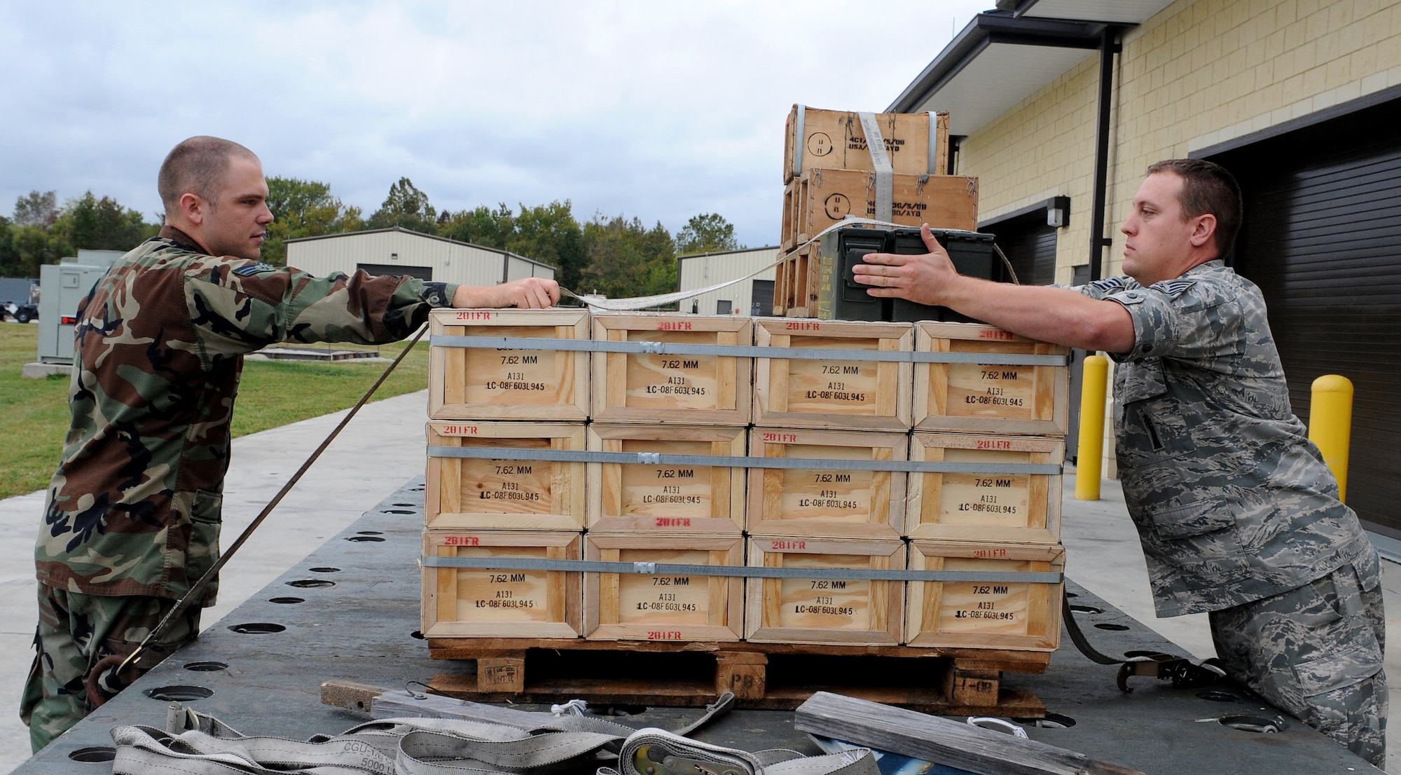 LANGLEY AIR FORCE BASE, Va. -- Senior Airman Robert Crockett, 1st Equipment Maintenance Squadron munitions storage crew member, and Staff Sgt. Matthew Johnson, 1st EMS munitions inspector, work together to secure ammunition before it is transported Oct. 17. The munitions flight provides the things that go boom. The flight can support any aircraft with missiles, bombs, small arms ammunition, and counter measures, including aircraft supporting Operation Noble Eagle.  (U.S. Air Force Photo/Airman 1st Class Zachary Wolf)