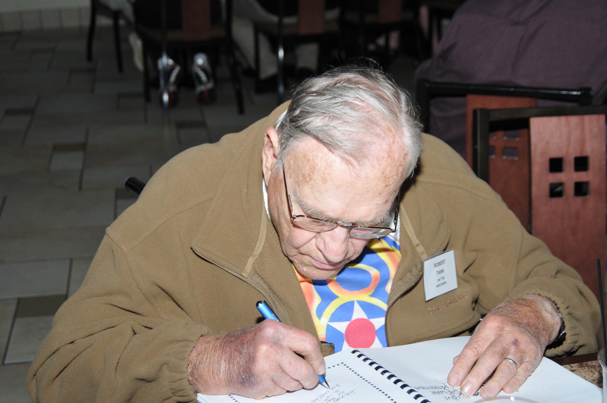 Robert Tank signs a book he wrote about his experiences in the 305th Bomb Group while stationed at Chelveston, England, during the group’s annual reunion in Colorado Springs, Co. Each year since 1976, the 305th Bombardment Group holds its annual reunion in various locations around the United States and in England. (U.S. Air Force photo/Kimberly Peterson)
