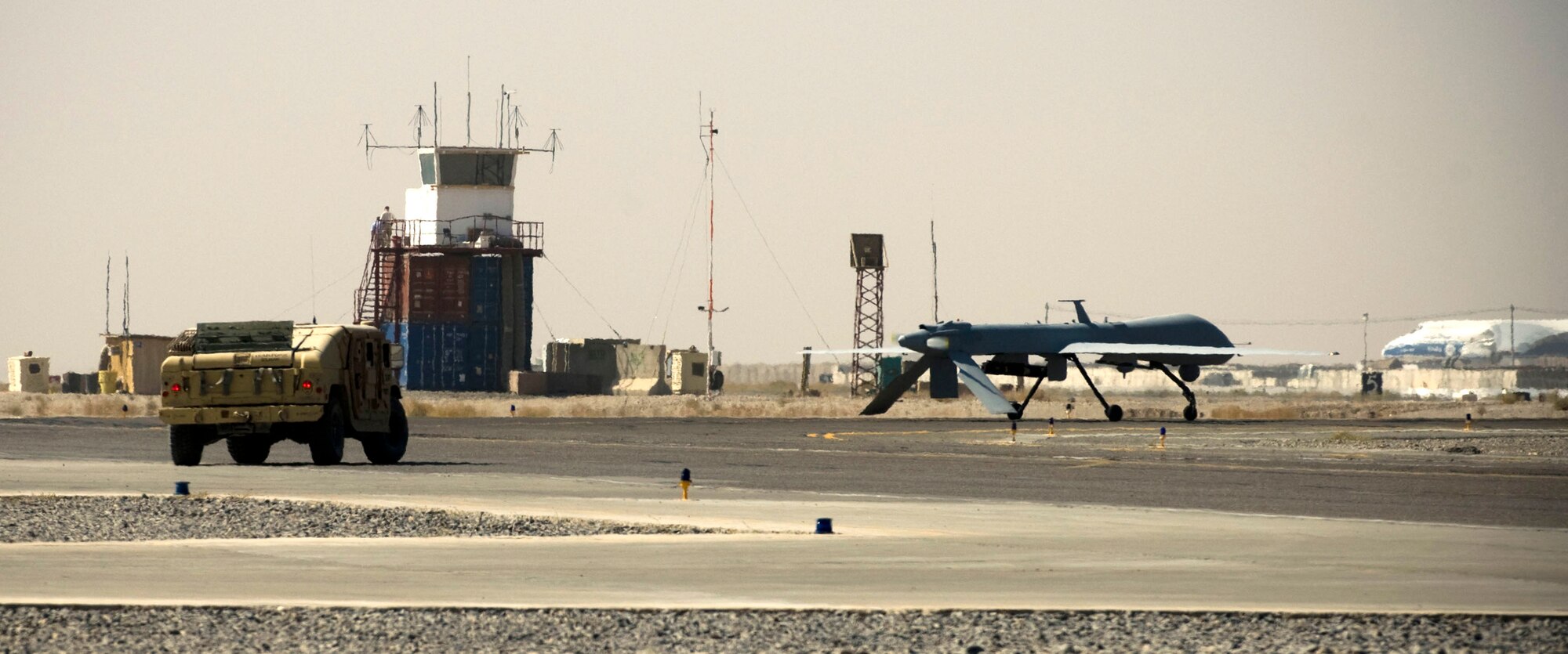 A security forces humvee escorts an MQ-1 Predator onto the runway at a base in southern Afghanistan, Oct. 25. Due to the small size of the aircraft and how unfamiliar many pilots are with it at the NATO-controlled air field, security forces must escort the Predator to prevent potential mishaps. (U.S. Air Force photo by Staff Sgt. Samuel Morse/Released)