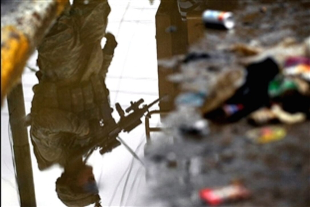 A U.S. Army soldier's reflection appears in a puddle as he patrols along side Iraqi soldiers in the Doura community of southern Baghdad, Iraq, Oct. 29, 2008. The soldier is assigned to 4th Infantry Division's 2nd Battalion, 4th Infantry Regiment, 1st Brigade Combat Team.