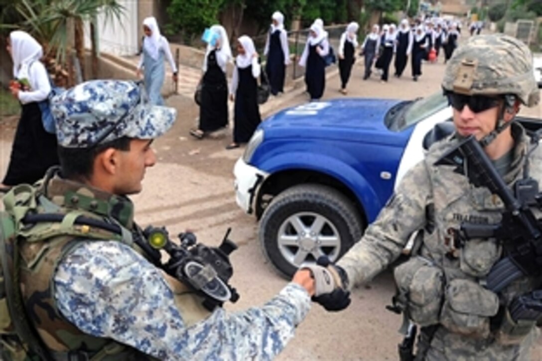 A U.S. Army soldier shakes hands with an Iraqi soldier standing security watch at a school in the Doura community of southern Baghdad, Iraq, Oct. 29, 2008. The U.S. soldier is assigned to the 4th Infantry Division's 2nd Battalion, 4th Infantry Regiment, 1st Brigade Combat Team.