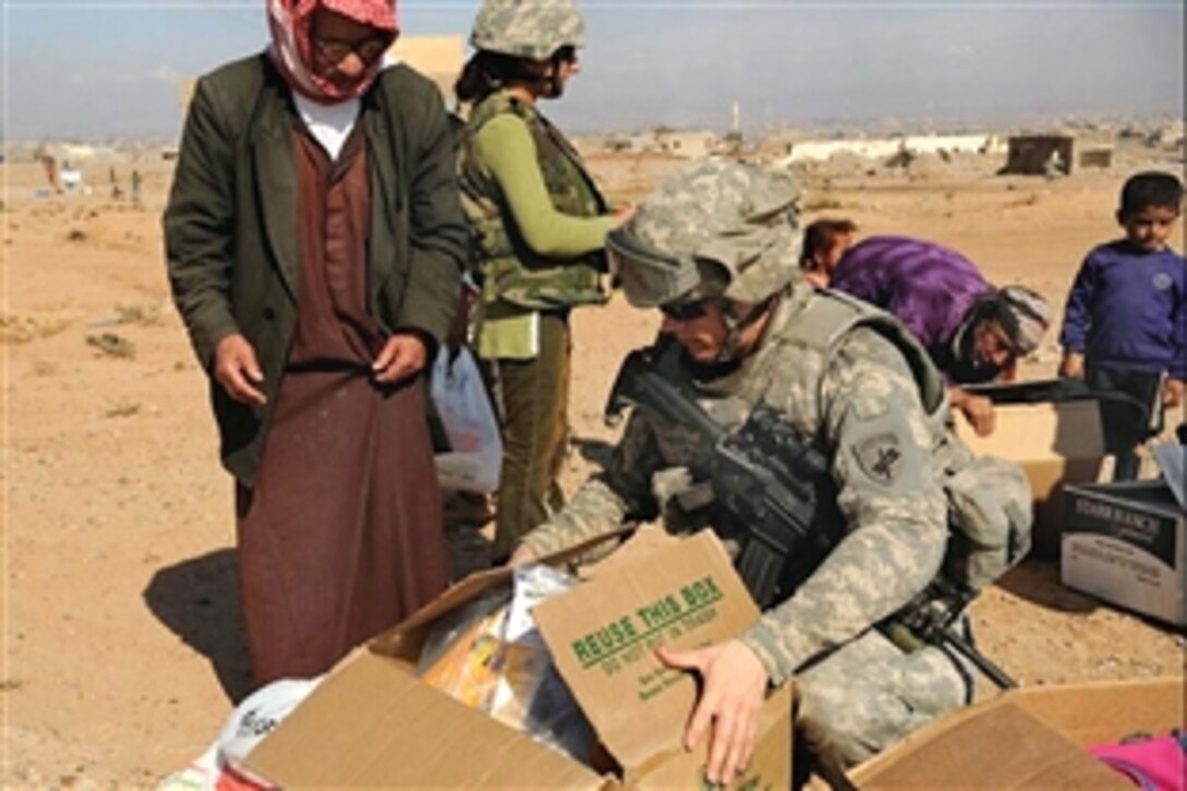 U.S. Army Staff Sgt. Adam Collins helps an Iraqi man take home a box of food, clothing and school supplies in Mamoon, Iraq, Oct. 31, 2008. Collins is assigned to the 415th Civil Affairs Battalion.
