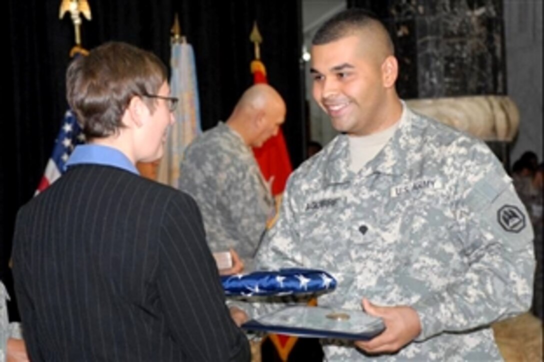 U.S. Army Spc. Jose Aguirre-Delgado receives an American flag from Lori Pietropaoli, deputy district director, U.S. Citizenship and Immigration Services' Rome District Office, Nov. 4, 2008, during a U.S. citizenship ceremony at Al Faw Palace on Camp Victory, Iraq.