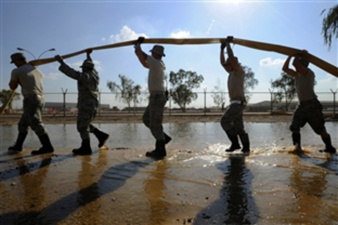 U.S. Air Force Senior Airman Paul Clayborn, Staff Sgt. Mervie Dotson, Tech. Sgt. Eric Miner, Senior Airman Christian Crespo and Airman 1st Class Gregory Hayes drain a hose on Joint Base Balad, Iraq, Nov. 3, 2008. All five are assigned to the 332nd Expeditionary Civil Engineer Squadron. 