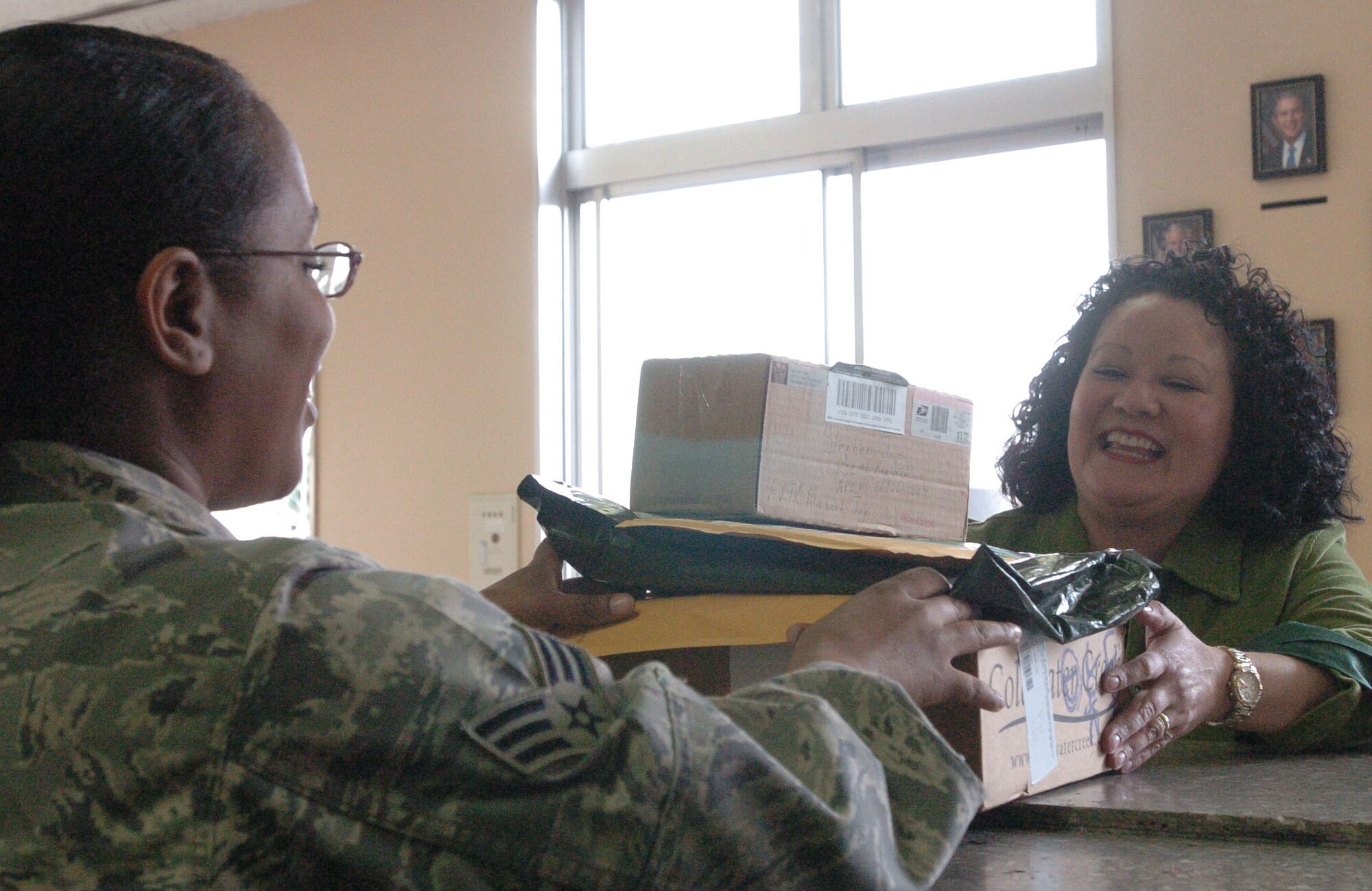YOKOTA AIR BASE, Japan-- Senior Airman Shyrhonda Hickman, 374th Communications Squadron, hands packages to Dora Jaje. As the holidays get closer, families of Yokota Air Base are reminded to check their mailboxes daily to allow plenty of storage for the 600 or more packages that the post office expects to recieve on a daily basis. (U.S. Air Force photo by Airman 1st Class Leandra D Hernandez) 