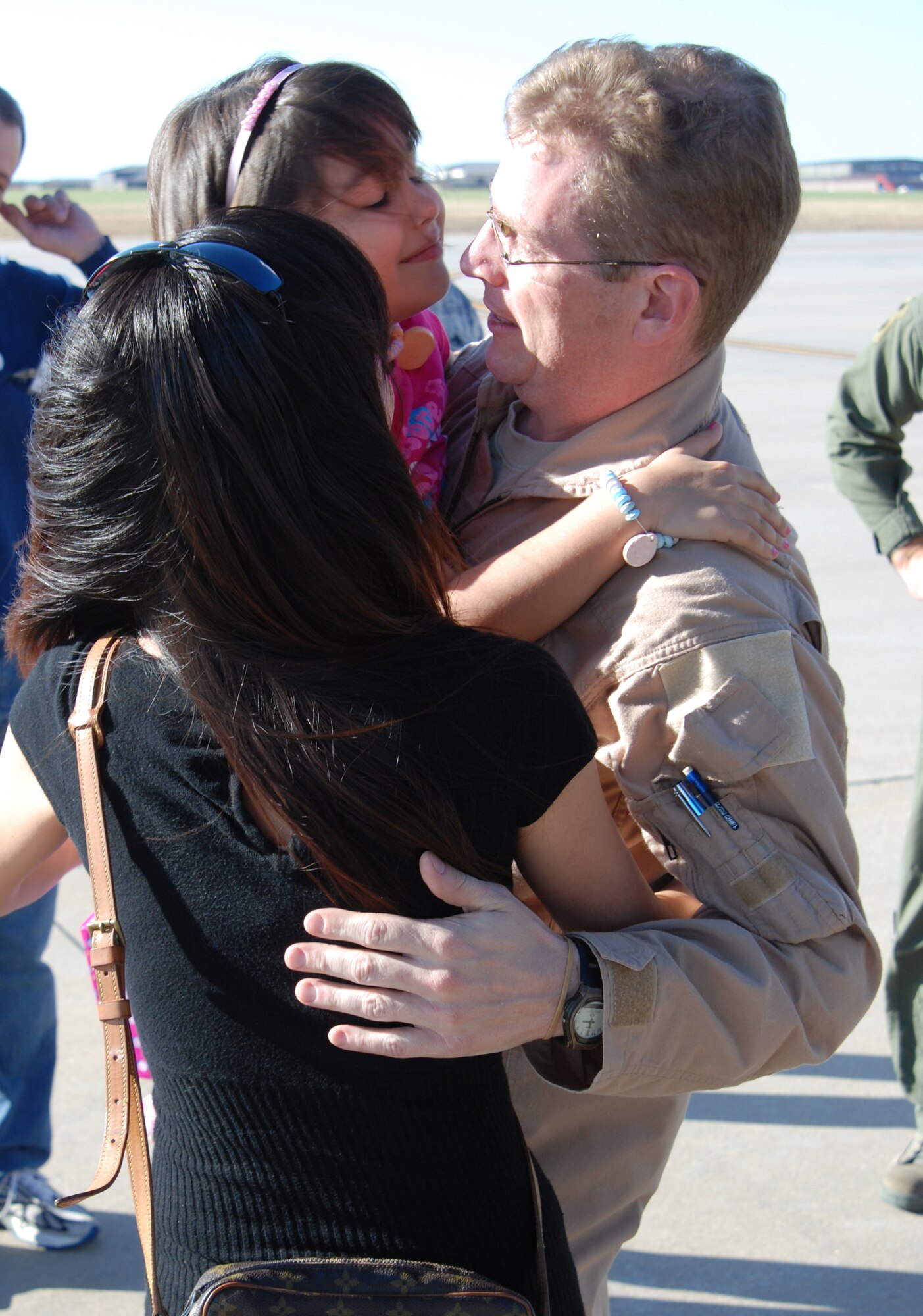 MCCONNELL AIR FORCE BASE, Kan. -- Tech. Sergeant Michael Webster, 349th Air Refueling Squadron, receives hugs from wife, Amy and 7-year-old daughter, Caren, while returning to McConnell, Nov. 2, from a deployment in Southeast Asia. (Photo by Airman 1st Class Jessica Lockoski)