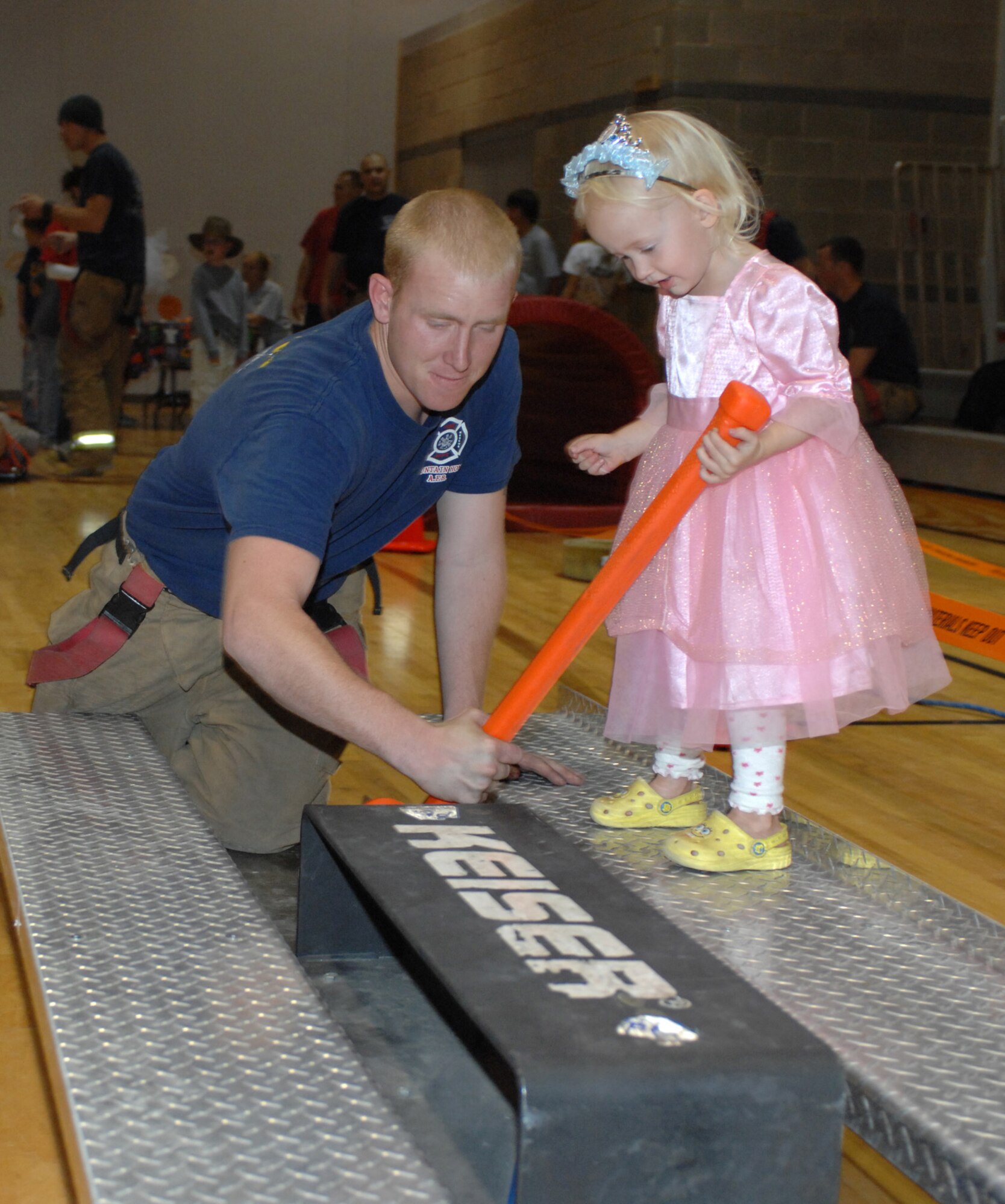 MOUNTAIN HOME AIR FORCE BASE, Idaho -- Airman 1st Class Scott O'Connell, 366th Civil Engineer Squadron, helps Ruby Franklin, age 2, complete the 366th CES fire emergency services obstacle course during the Boo Bash, held at the youth center Oct. 24. There were over 600 Gunfighters and family members who attended this year's Boo Bash, with more than $900 raised for youth programs and clubs. (U.S. Air Force photo/Airman 1st Class Ashley Tank)