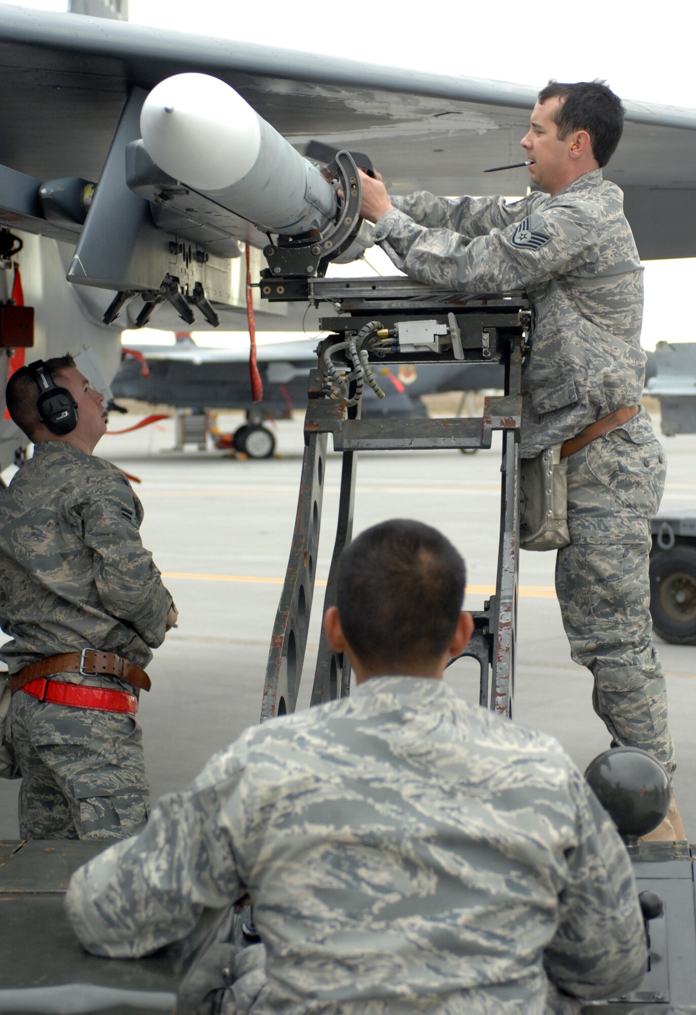 MOUNTAIN HOME AIR FORCE BASE, Idaho -- Staff Sgt Robert Bruner (right), Airman 1st Class Emad Hamedeyyeh (middle), and Airman 1st Class Robert Lawson (left), all 389th Aircraft Maintenance Unit weapons loaders, work as a team to load and secure a weapon during the base's weapons load crew of the quarter competition Oct. 31. The 389th AMU took the win with a time of 19:56 and the 391st crew finished second with a time of 23:42. (U.S. Air Force photo/ Airman Debbie Lockhart)