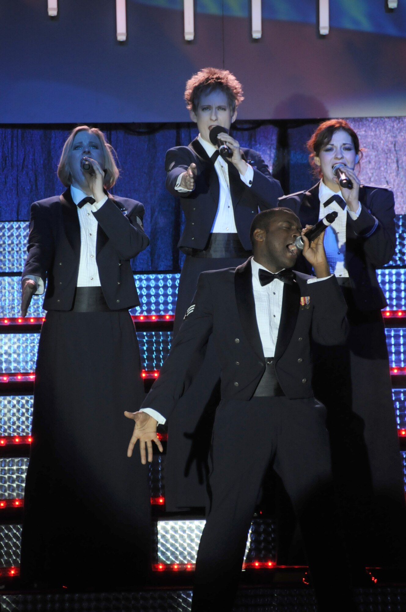 Senior Airman Tommy Crutcher, 81st Force Support Squadron Services, takes center stage for Lee Greenwood’s “God Bless the USA” with Tech. Sgt. Bridgett Johnson, left, Moody AFB, Ga.; Senior Airman April Vollm, Dyess AFB, Texas; and 1st Lt. Darci Day, Tinker AFB, Okla.  (U.S. Air Force photo by Kemberly Groue)