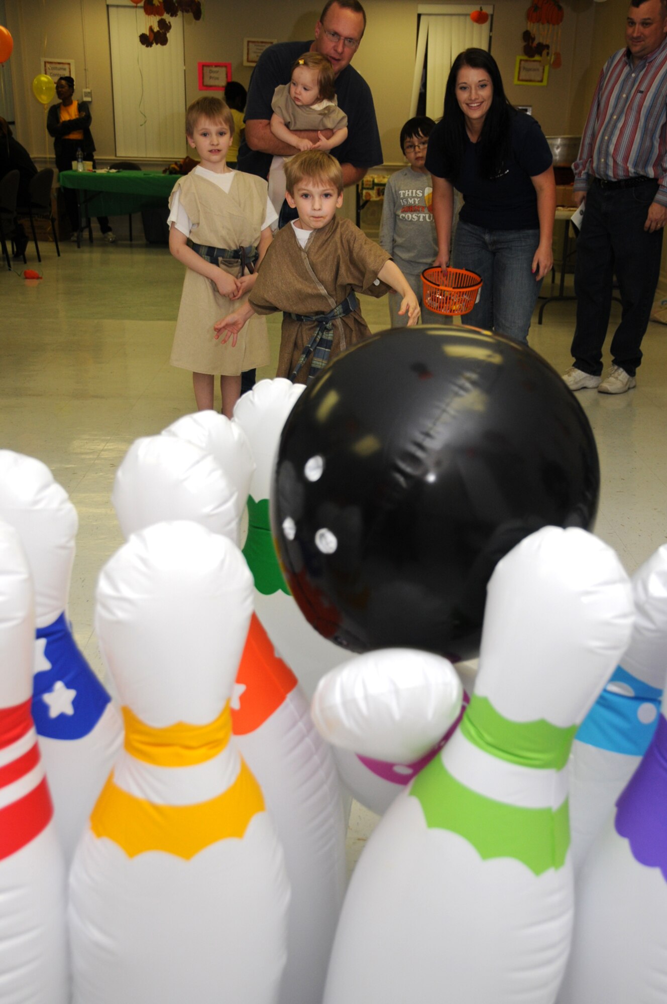Tristian Mallory, 5, plays inflatable bowling as his 7-year-old brother Jabin waits his turn.  Their dad, Chaplain (Capt.) Charles Mallory, holds their 1-year-old sister, Jennalyn, as Airman Basic Tiffany Rogers, a volunteer from the 336th Training Squadron, cheers them on.  (U.S. Air Force photo by Kemberly Groue)