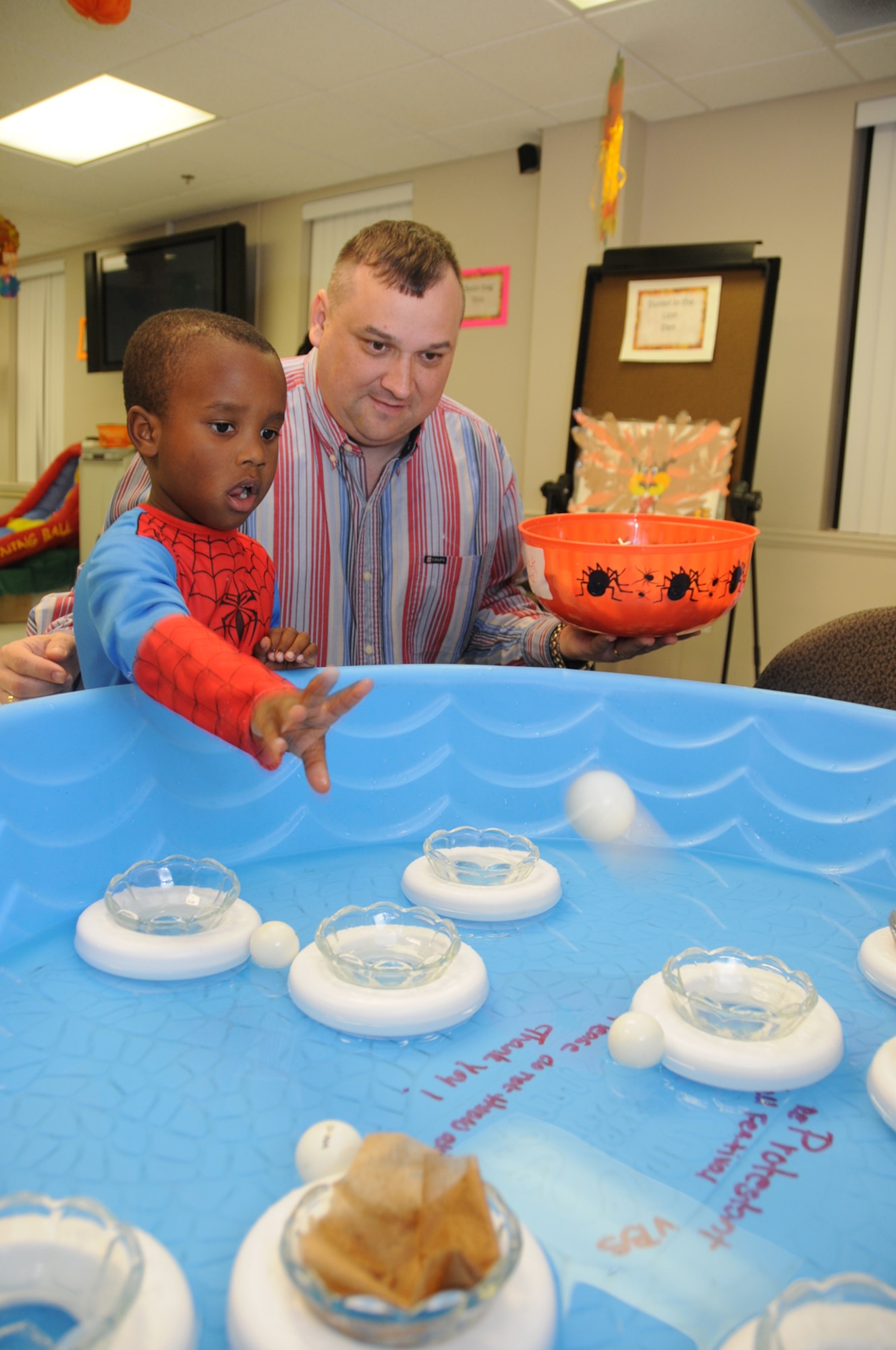 Four-year-old Brian Louis Jr. plays the floating ring toss game with Chaplain (Capt.) Scott Jobe at the chapel’s harvest festival, Friday at the Triangle Chapel annex.  Brian’s parents, retired Tech. Sgt. Brian and Dierdre Louis of Ocean Springs, are members of Keesler’s gospel service.  The event included games, food, candy and a costume contest.  (U.S. Air Force photo by Kemberly Groue)