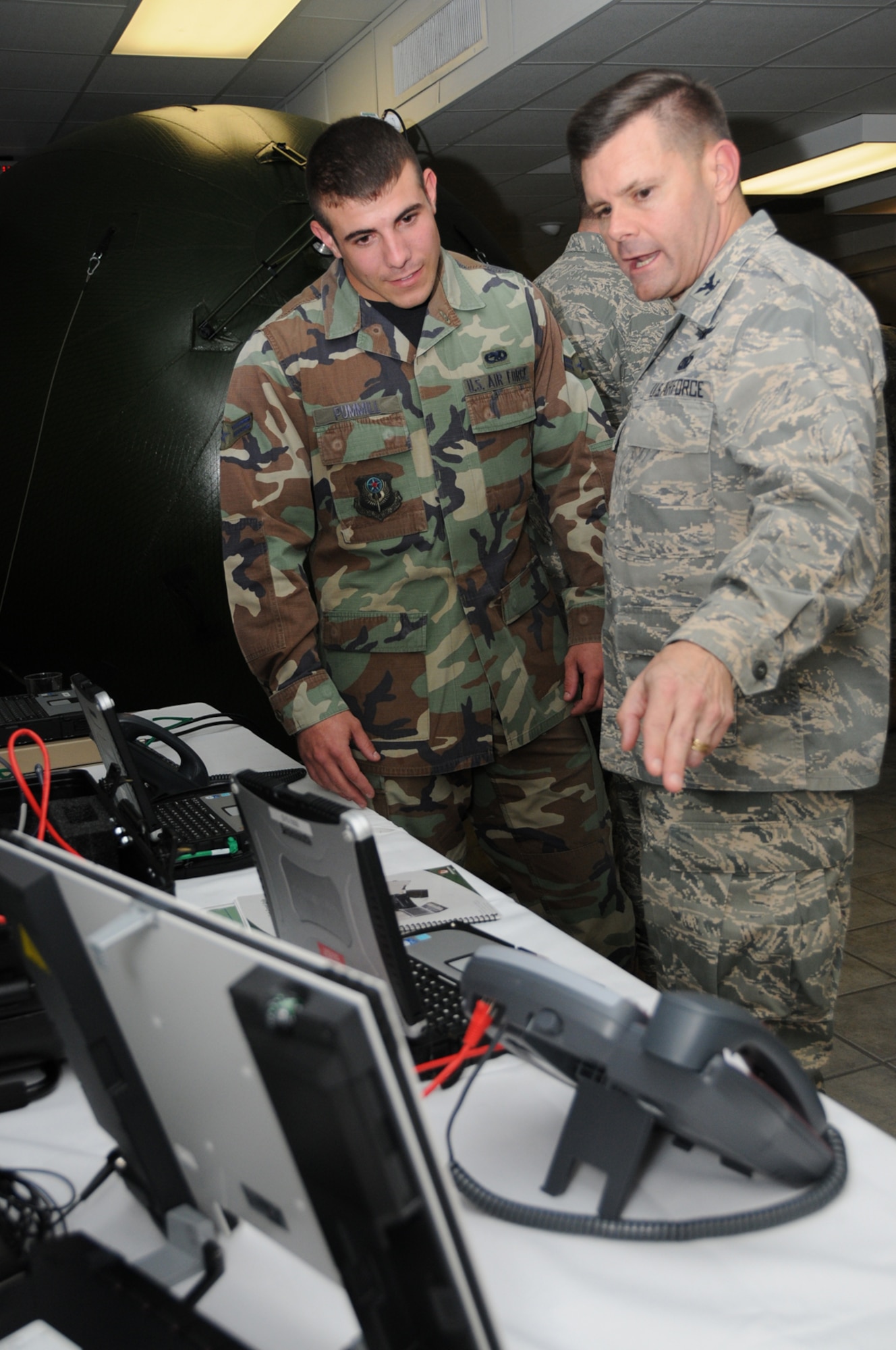Airman 1st Class Matthew Pummill, left, Hurlburt Field, Fla., talks to Col. Mike Lewis, director of communications for Air Force Pacific Command at Hickam Air Force Base, Hawaii, discuss the benefits of a secure high-speed agile reachback kit used on short-notice deployments.  They attended the Scope Warrior dining-in Oct. 29 at the Locker House Dragon’s Den.  (U.S. Air Force photo by Kemberly Groue)