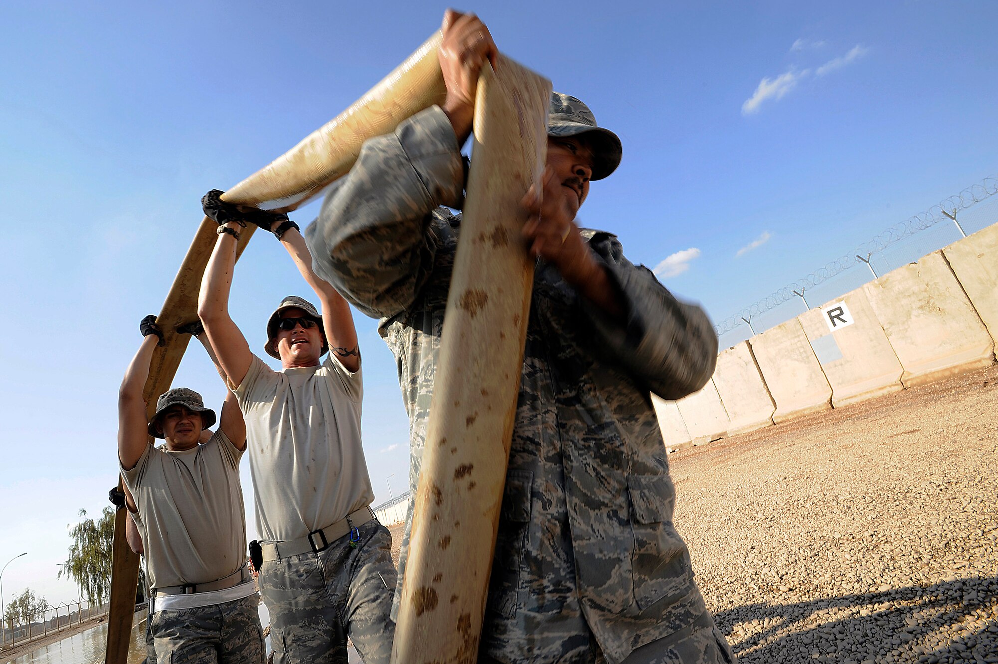 Staff Sgt. Mervie Dotson (front to back), Tech. Sgt. Eric Miner and Senior Airman Christian Crespo drain a hose while pumping floodwater to an unused yard Nov. 3 at Joint Base Balad, Iraq. All three Airmen are utilities systems technicians with the 332nd Expeditionary Civil Engineer Squadron. Sergeant Dotson, a native of Tyler, Texas, is deployed from Barksdale Air Force Base, Ga. Sergeant Miner, a native of Concord, N.H., is deployed from McConnell AFB, Kan. Airman Crespo, a native of Dallas, is deployed from Malmstrom AFB, Mont. (U.S. Air Force photo/Airman 1st Class Jason Epley) 
