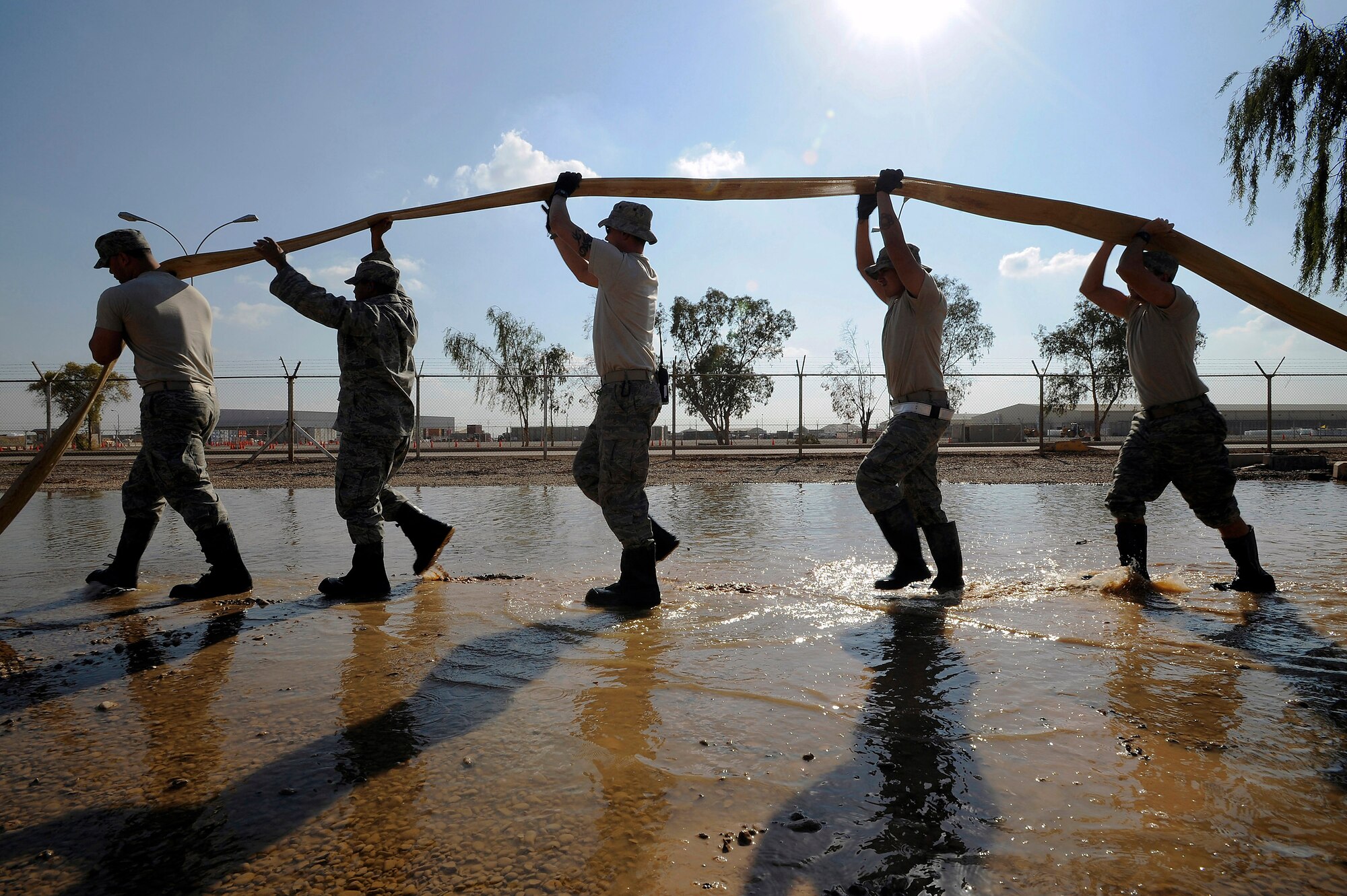 Senior Airman Paul Clayborn, Staff Sgt. Mervie Dotson, Tech. Sgt. Eric Miner, Senior Airman Christian Crespo and Airman 1st Class Gregory Hayes drain a hose while pumping floodwater out of a low-lying area Nov. 3 at Joint Base Balad, Iraq. All five Airmen are utility system technicians with the 332nd Expeditionary Civil Engineer Squadron. Airman Clayborn, a native of Arlington, Texas, is deployed from Andrews Air Force Base, Md. Sergeant Dotson, a native of Tyler, Texas, is deployed from Barksdale AFB, La. Sergeant Miner, a native of Concord, N.H., is deployed from McConnell AFB, Kan. Airman Crespo, a Dallas native, is deployed from Malmstrom AFB, Mont. Airman Hayes, a native of Lancaster, S.C., is deployed from Schriever AFB, Colo. (U.S. Air Force photo/Airman 1st Class Jason Epley) 
