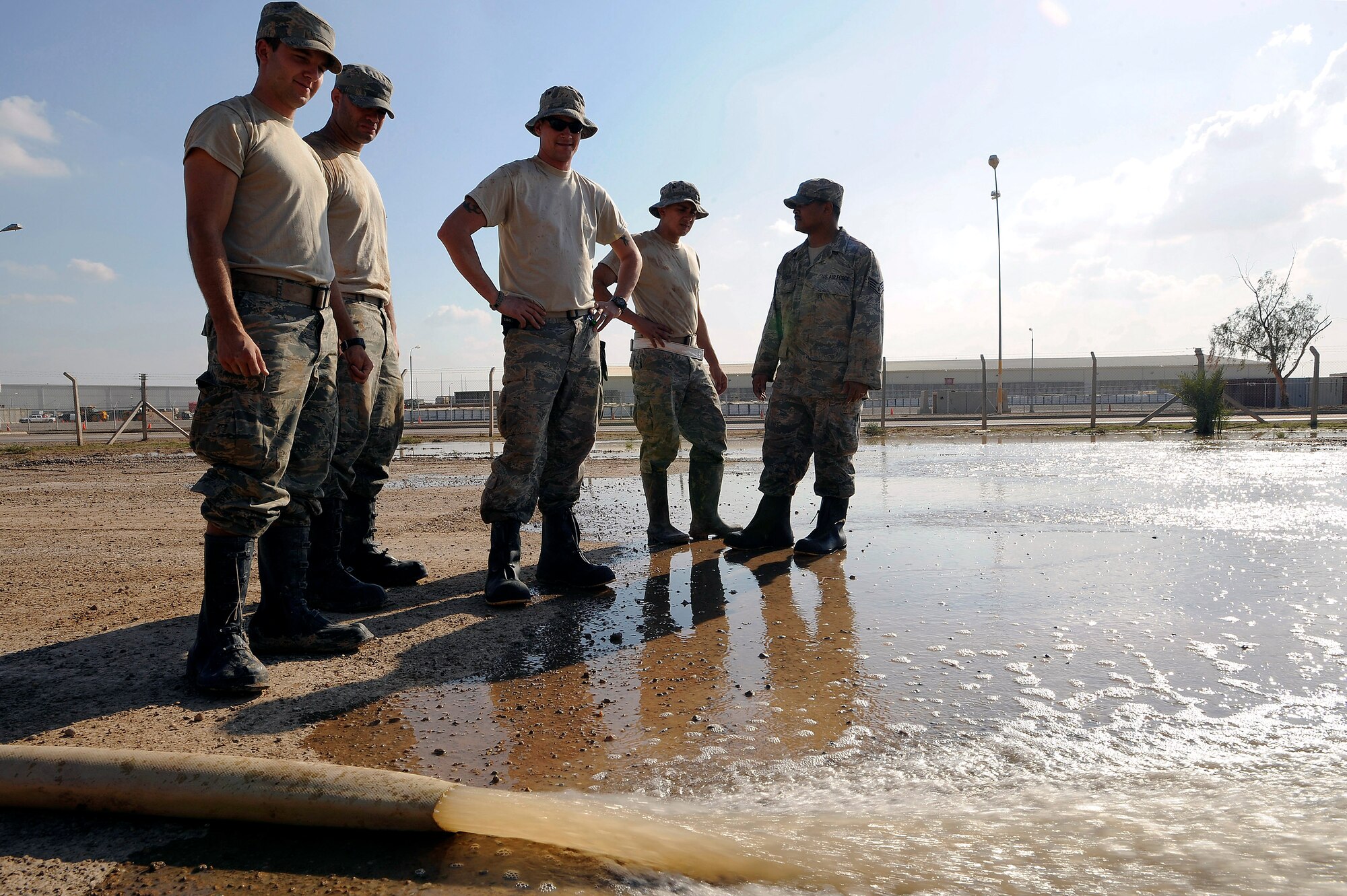 Airman 1st Class Gregory Hayes, Senior Airman Paul Clayborn, Tech. Sgt. Eric Miner, Senior Airman Christian Crespo and Staff Sgt. Mervie Dotson watch as floodwater from one yard flows into an used yard Nov. 3 at Joint Base Balad, Iraq. Pumping the floodwater allows maintenance technicians to access a radio tower on base. All five Airmen are utilities systems technicians with the 332nd Expeditionary Civil Engineer Squadron. Airman Clayborn, a native of Arlington, Texas, is deployed from Andrews Air Force Base, Md. Sergeant Dotson, a native of Tyler, Texas, is deployed from Barksdale AFB, La. Sergeant Miner, a native of Concord, N.H., is deployed from McConnell AFB, Kan. Airman Crespo, a Dallas native, is deployed from Malmstrom AFB, Mont. Airman Hayes, a native of Lancaster, S.C., is deployed from Schriever AFB, Colo. (U.S. Air Force photo/Airman 1st Class Jason Epley) 

