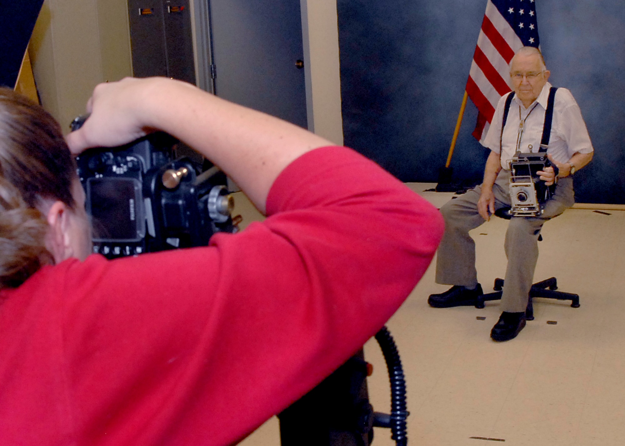Holding an antique 'Speed Graphic' camera, 1st. Lt. James Spence has his portrait taken by Roberta McDonald at Multimedia Services during his Oct. 31 visit to Peterson AFB. Lieutenant Spence is a former Peterson Field Photo Lab commander, stationed here from the Summer of 1942 until the Fall of 1944. (Air Force photo/Rob Bussard)