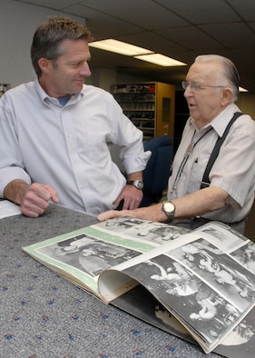 Public Address Lead Gary Thomas and 1st Lt. (ret.) James Spence discuss memories from a 1943 the 35th Photo Tech Unit Yearbook of Guam, where Lieutanant Spence transferred after his assignment at Peterson Field. (Air Force photo/Rob Bussard)