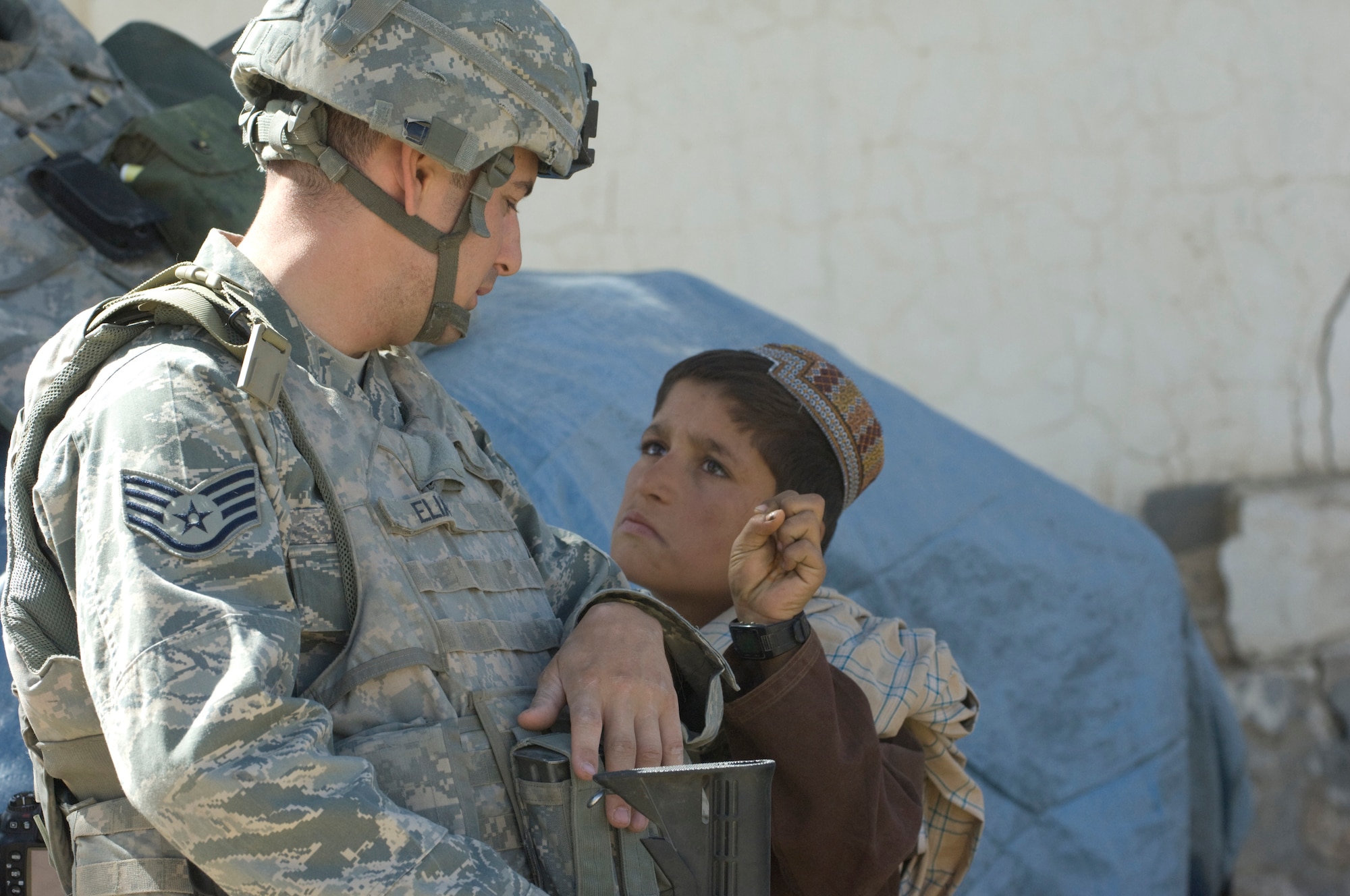 QALAT, Afghanistan -- Air Force Staff Sgt. Don Elias talks with an Afghan boy while providing security at a veterinary outreach held by the Zabul Provincial Reconstruction Team recently. The PRT provided free treatment to the nomadic Kuchi tribe's livestock. Sergeant Elias is deployed to the PRT as the force protection NCOIC from Wright-Patterson Air Force Base, Ohio. He is a native of Buffalo, N.Y. (U.S. Air Force photo/Master Sgt. Keith Brown)