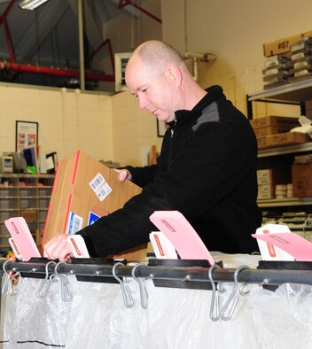 Mark Burrows, 100th Communications Squadron Post Office receipt and dispatch operative, prepares outgoing bags of mail. Mail brought in by customers is sorted into APO and non-APO areas. The non-APO mail is broken down into five different stateside locations -- New York, Miami, Chicago, Dallas and San Francisco. When it reaches those destinations, it is then redistributed all over the states. Parcels and letters for APO addresses are sorted separately into different APO areas. this time of year, Mr. Burrows said the post office receives about 30 bags of mail daily for the five U.S. locations (approximately 30 to 40 boxes). For APO addresses, they usually receive about 15 bags per day. Nearer the holidays in December, the amount of stateside mail at least quadruples, and APO more than doubles. The receipt and dispatch staff also pick up mail from mailboxes around base and bring it back to the post office to process  and send it out to its destination. (U.S. Air Force photo by Karen Abeyasekere)