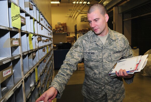 Senior Airman Joshua Bland, 100th Communications Squadron Post Office postal clerk, pitches mail Nov. 4. Mail is delivered to the post office daily, and is sorted by the postal staff. It is broken down into groups of 100 mailbox numbers, such as box numbers 800 to 900, then from there transferred to each individual mailbox. (U.S. Air Force photo by Karen Abeyasekere)