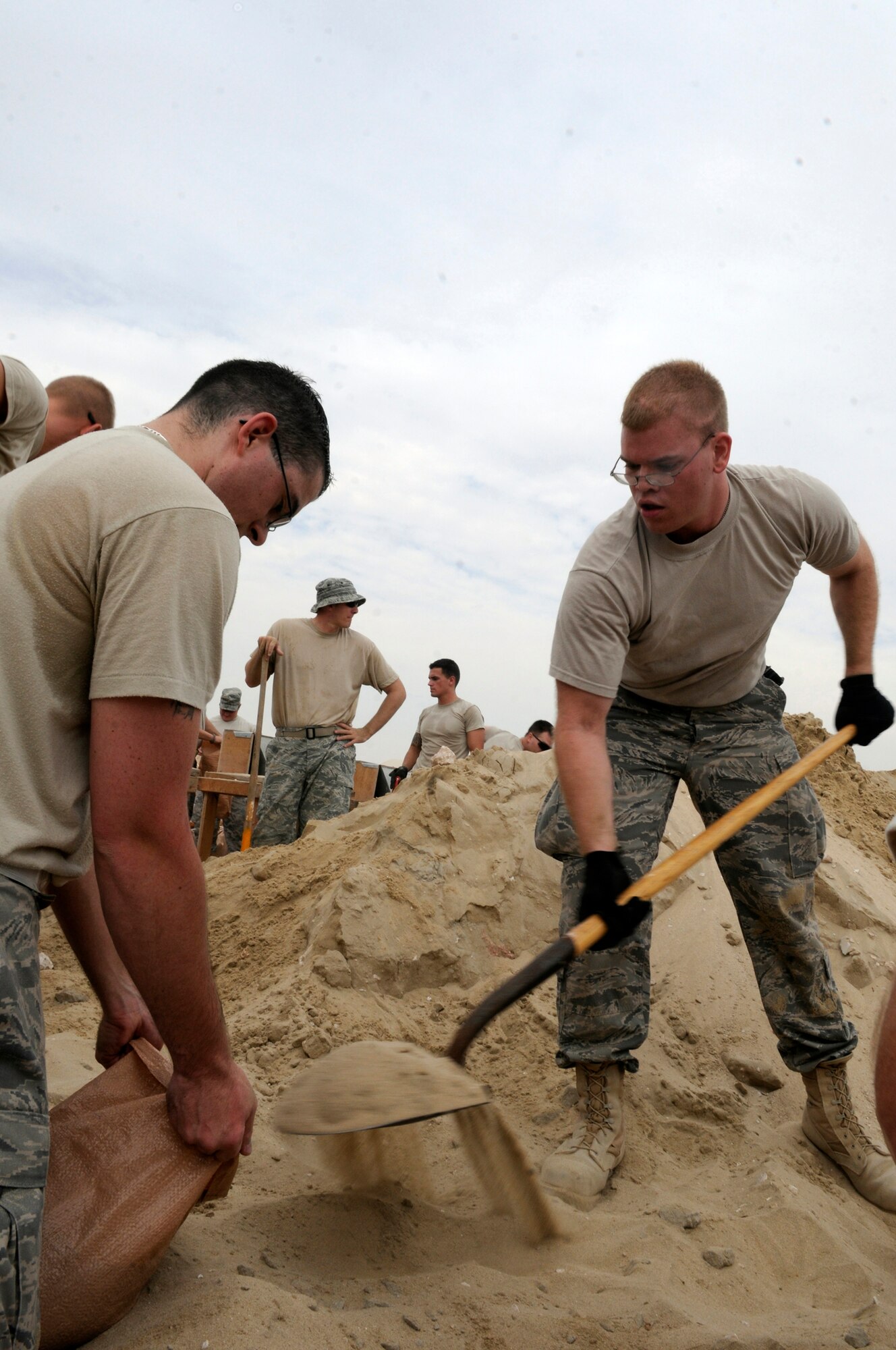 Staff Sgt. John Carlson and Senior Airman Tyson Powell, both assigned to the 379th Expeditionary Communications Squadron, fill sand bags Nov. 4, at an undisclosed air base in Southwest Asia.  With Sergeant Carlson shoveling and Airman Powell holding the sandbag, the two are doing their part to fortify emergency bunkers.  Sergeant Carlson, a native of Tacoma, Wash., is deployed from Incirlik Air Base, Turkey.  Airman Powell hails from Tomah, Wis., and is deployed from Royal Air Force Alconbury, England.  Both are deployed in support of Operations Iraqi and Enduring Freedom and Joint Task Force-Horn of Africa.  (U.S. Air Force photo by Tech. Sgt. Michael Boquette/Released)