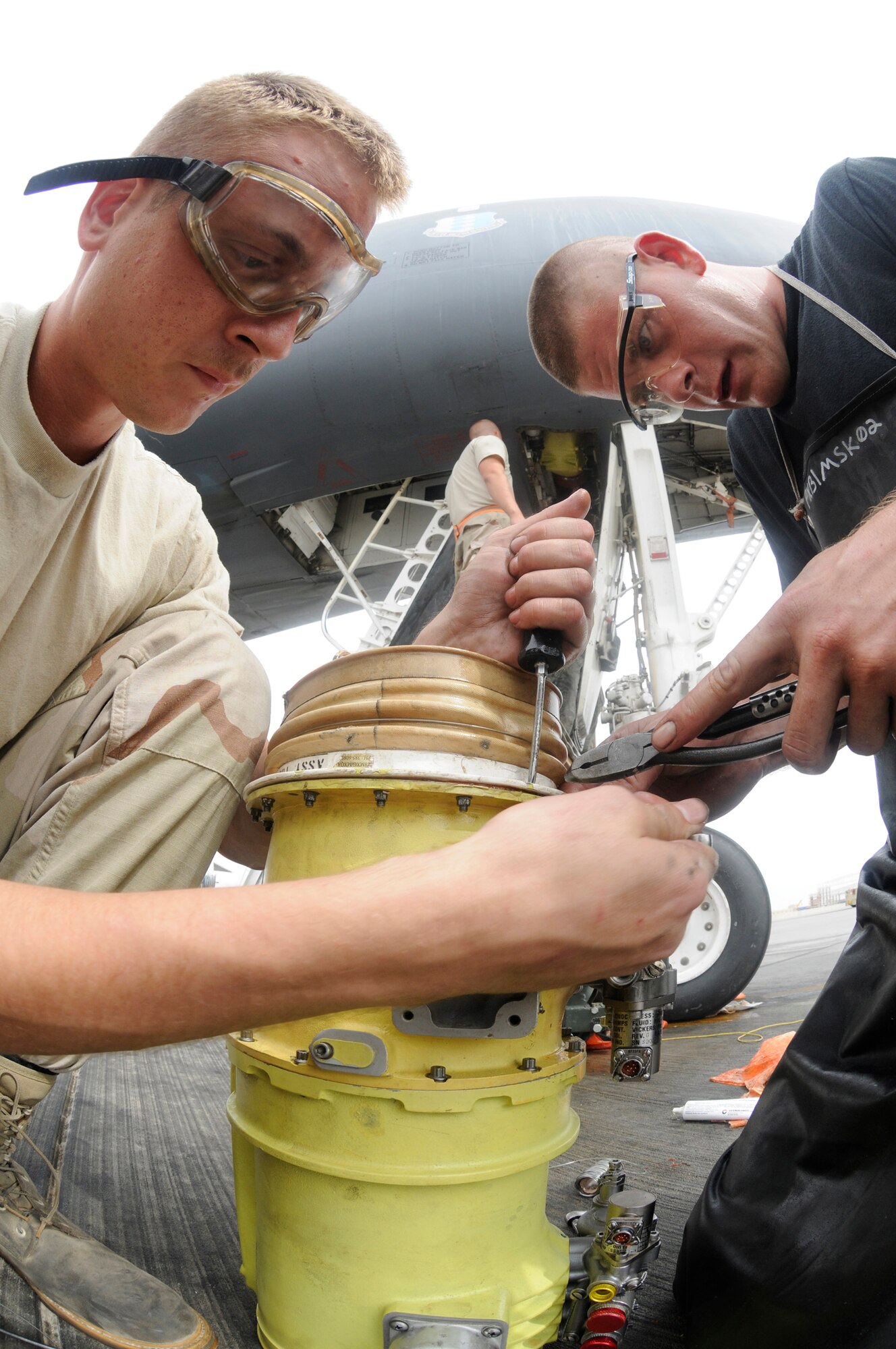 Airman 1st Class Kyle Stinger tightens screws while Senior Airman David Wonsitle applies safety wire to a B-1B Lancer air recirculation loop blower Nov. 4, at an undisclosed air base in Southwest Asia.  Both are aircraft electrical and environmental journeymen assigned to the 379th Expeditionary Aircraft Maintenance Squadron, deployed from Ellsworth Air Force Base, S.D., in support of Operations Iraqi and Enduring Freedom.  Airman Stinger is a native of St. Louis, Mo., and Airman Wonsitle hails from Abilene, Texas.  (U.S. Air Force photo by Staff Sgt. Darnell T. Cannady/Released)