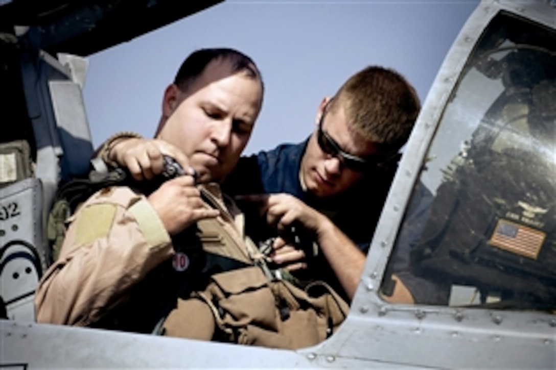 U.S. Air Force Senior Airman Benjamin Connery helps Maj. Erik Knauff buckle into an A-10 Thunderbolt II on Bagram Airfield, Afghanistan, Oct. 18, 2008. Connery is a 455th Expeditionary Aircraft Maintenance Squadron A-10 crew chief and Knauff is a flight safety officer and pilot. 