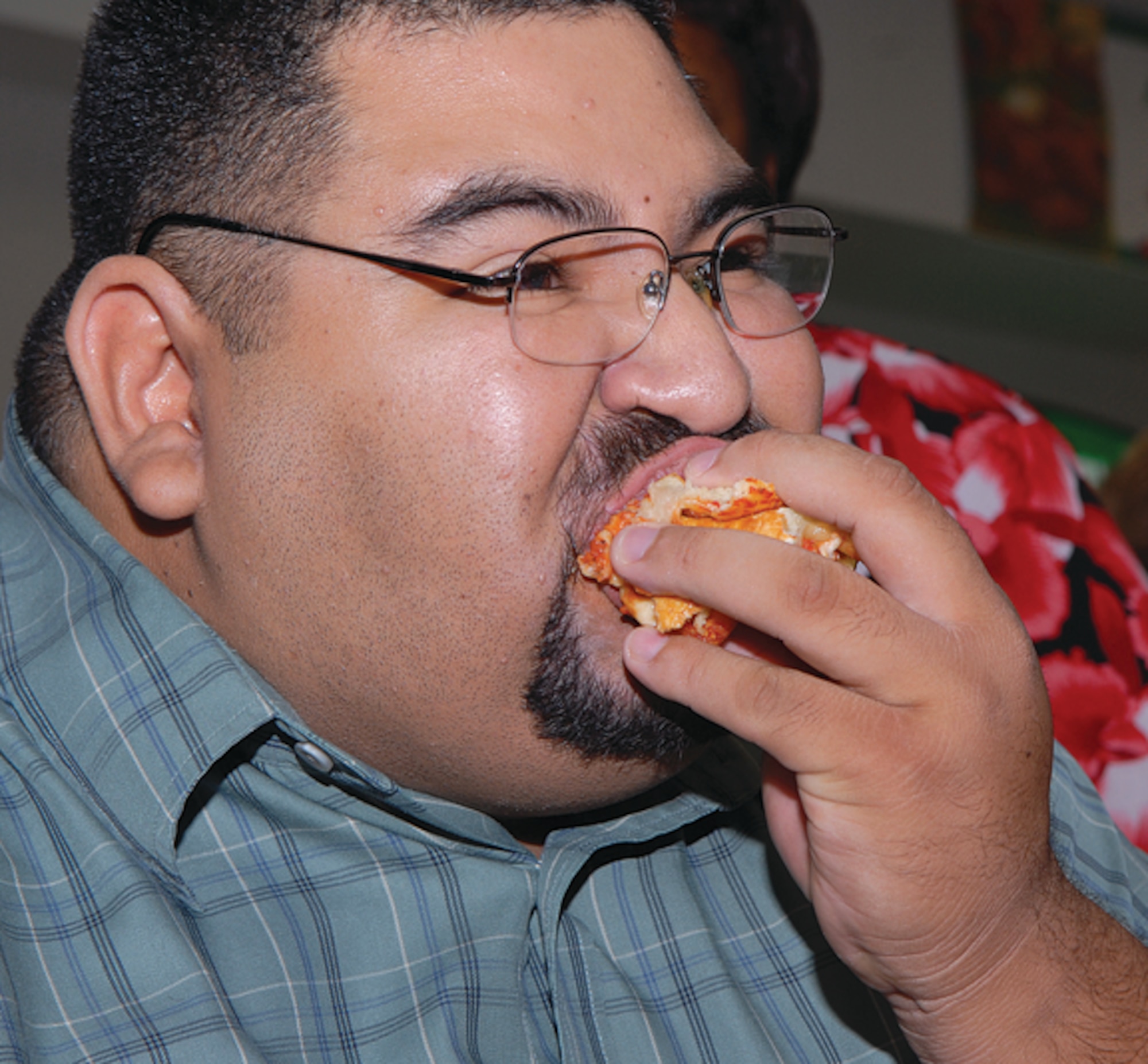 Ernest Haros rolls up his slice of pizza during Anthony's Pizza Eating Contest held at the base exchange food court. (U.S. Air Force photo/ Airman 1st Class Ronifel Yasay.)