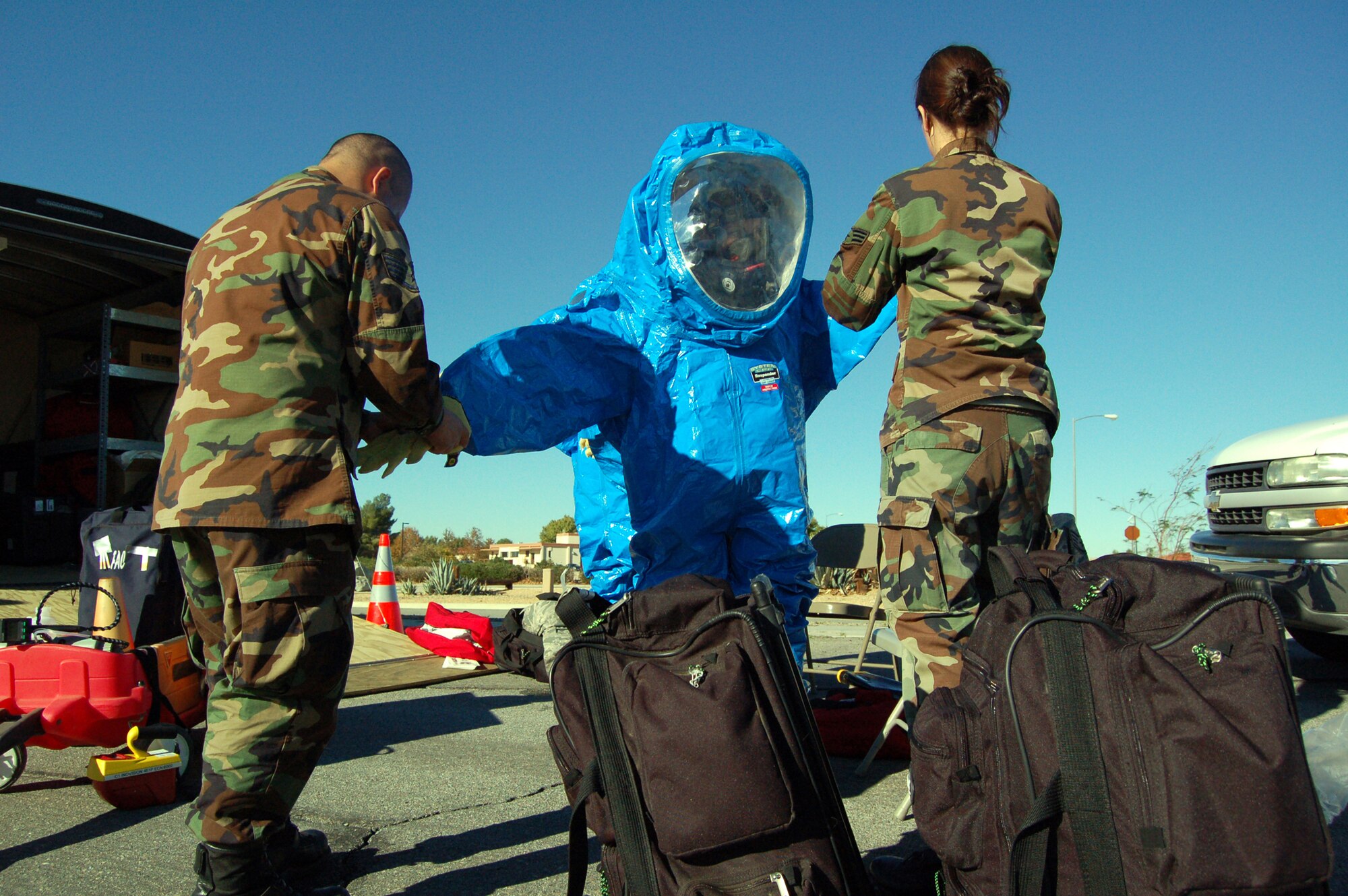 Staff Sgt. Halder Hernandez (left), 95th Aerospace Medicine Squadron bioenvironmental engineer craftsman, and Senior Airman Shannon Stewart (right), bioenvironmental engineer journeyman, help Staff Sgt. Amanda Lublin don a suit Nov. 6 as part of a scenario for the Chemical, Biological, Radiological and Nuclear Challenge. The challenge tests all AFMC bases' bioenvironmental flights on their CBRN detection or identification capabilities. (Air Force photo by Senior Airman Julius Delos Reyes)