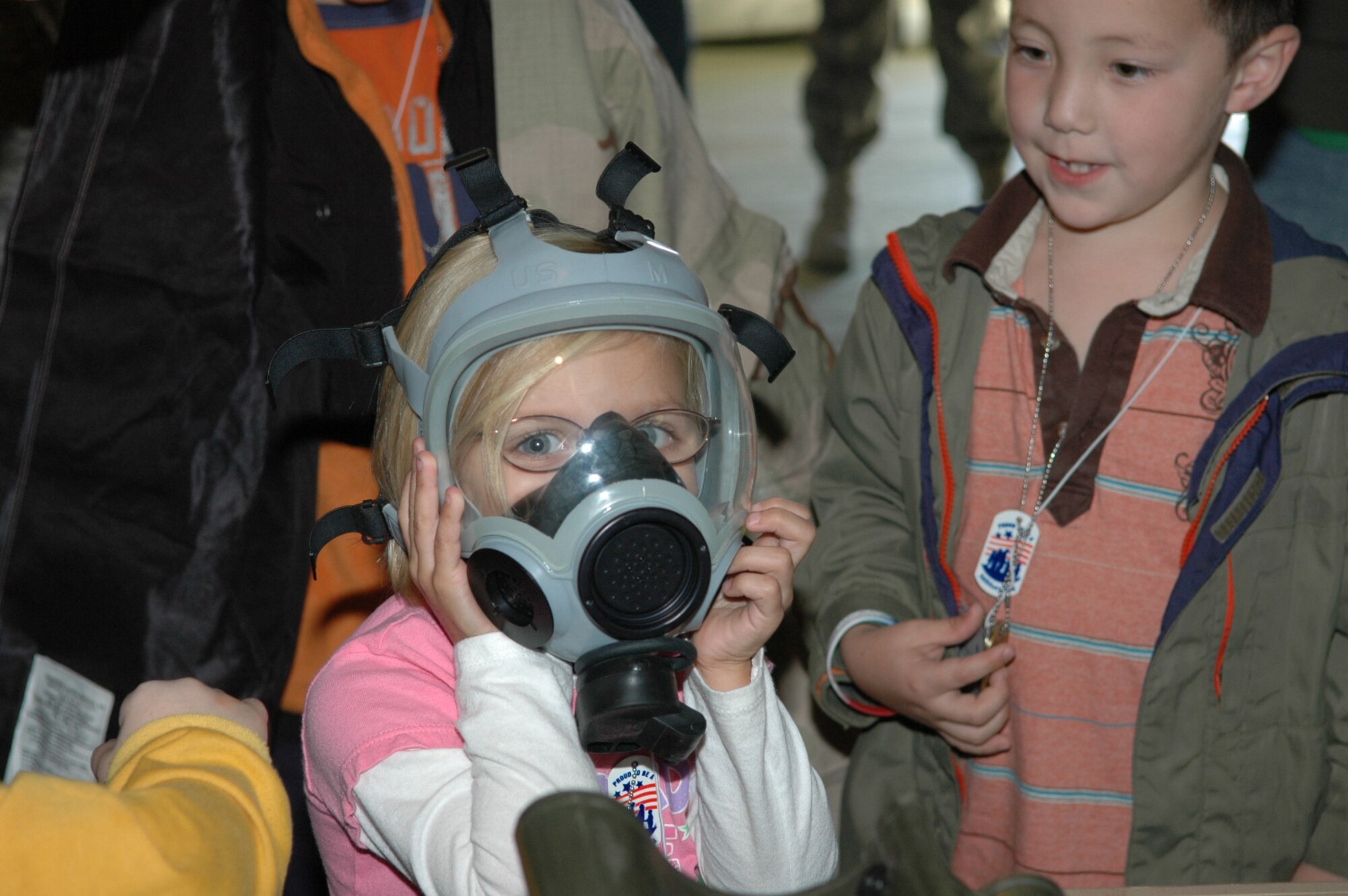 Steffanie Hutchison, 5, tries on a gas mask while deployed to Gator Air Base.  U. S. Air Force photo by Sue Sapp