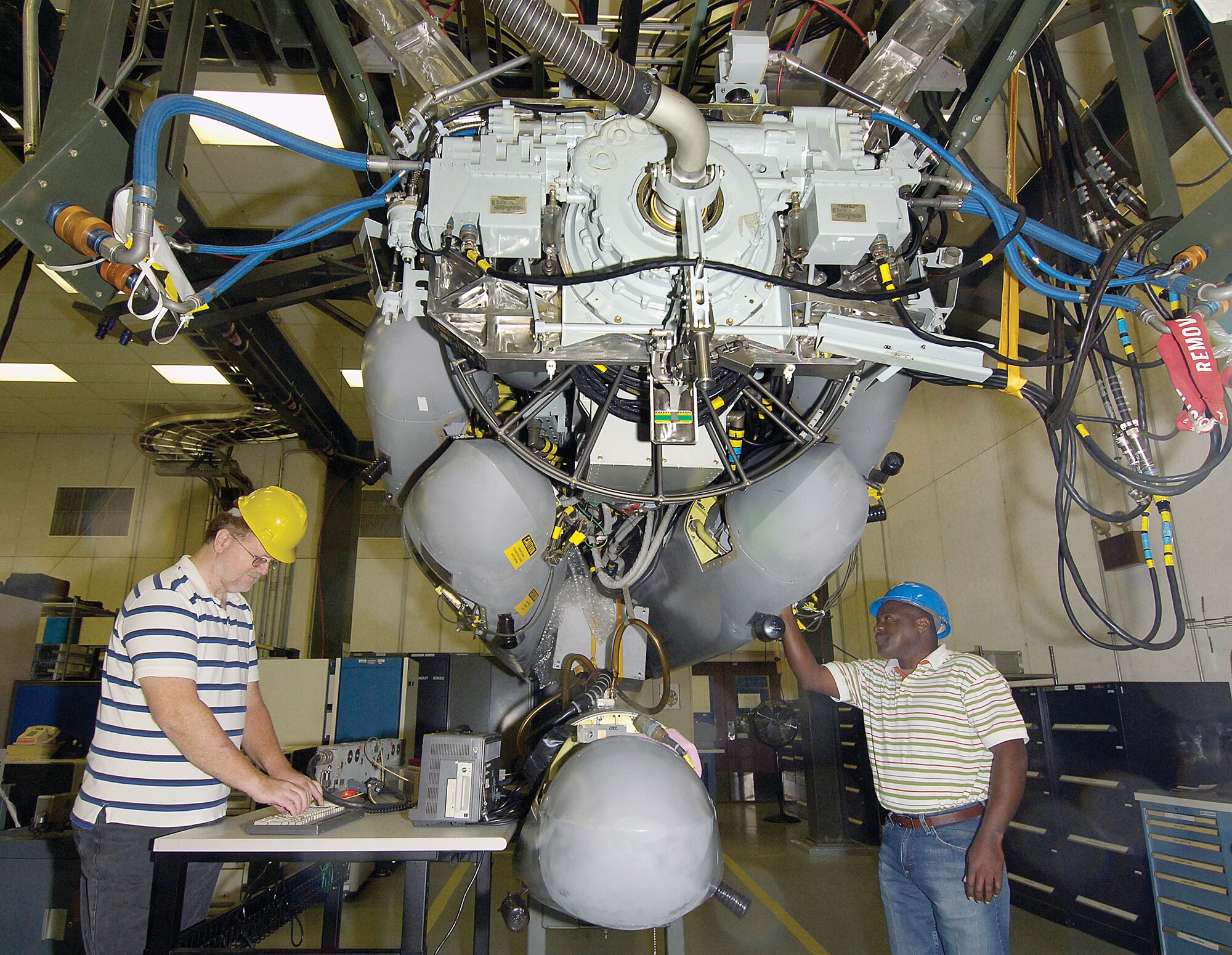 Don Cotter and Scottie Huey, from left, both electrical engineers in the Avionics Integration Support Facility, are dwarfed by a Common Strategic Rotary Launcher used in software maintenance and field support for the cruise missile community.  The launcher would be in a B-52 and because of its nuclear capabilities will be a featured stop during the Tinker Nuclear Immersion Day Nov. 14.  The day will highlight areas where Tinker supports the nuclear mission. (Air Force photo/Margo Wright)
