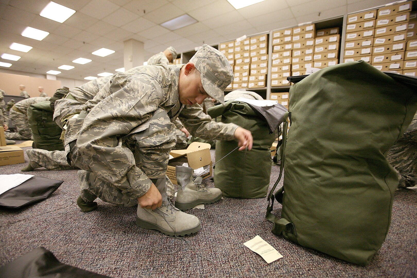 11/5/2008 - Air Force Basic Military Training trainee Shayne Wooden, 321st Training Squadron, Flight 075, laces up his boots during the initial clothing issue Nov. 5. He is among the first group of Air Force recruits to experience an additional 14 days of training as BMT expands from 6.5 to 8.5 weeks. The additional time will enhance and reinforce current war skills training. (USAF photo by Robbin Cresswell)  