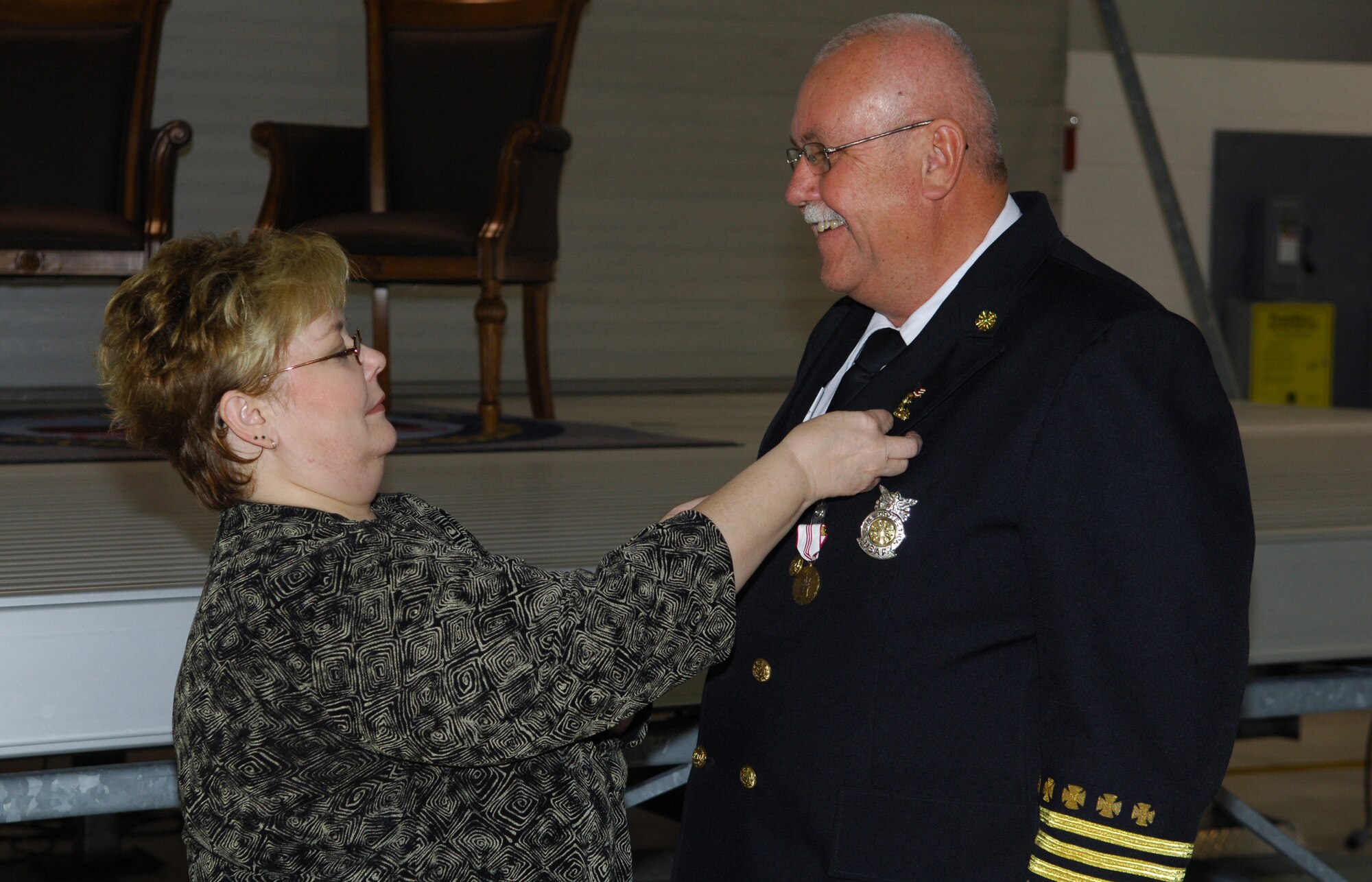 MINOT AIR FORCE BASE, N.D. -- Janet Clifford places a retirement pin on the jacket of husband Fire Chief James D. Clifford during his retirement ceremony here Oct. 31. Chief Clifford was selected as base fire inspector in March 1986, promoted to Assistant Chief of Fire Prevention in 1992 and selected as Fire Chief in July 2001. Chief Clifford has dedicated 33 years of his life toward faithful service to his country and community. (U.S. Air Force photo by Senior Airman Cassandra Jones)