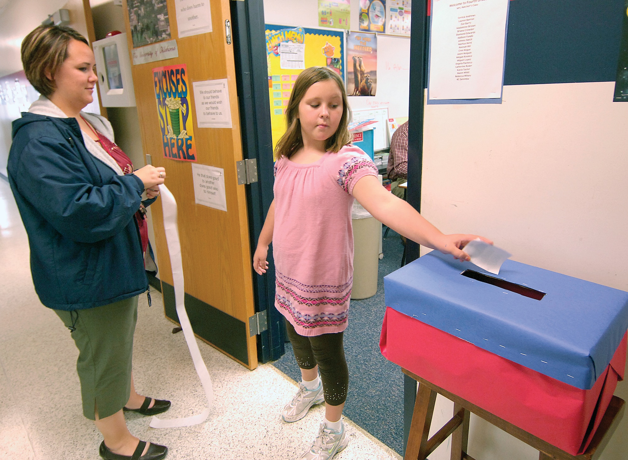 Tinker Elementary School  fourth-grader Brianna Zenzen casts her vote Oct. 30 for president as teacher Cindy Yarnell readies an “I voted” sticker for the student. Many students had strong opinions about their presidential hopeful. Some students had watched every debate, cited reasons for their choices, often picking a candidate opposite their parents’ favorite. When the votes were tallied, Barack Obama came out the winner. (Air Force photo/Margo Wright)