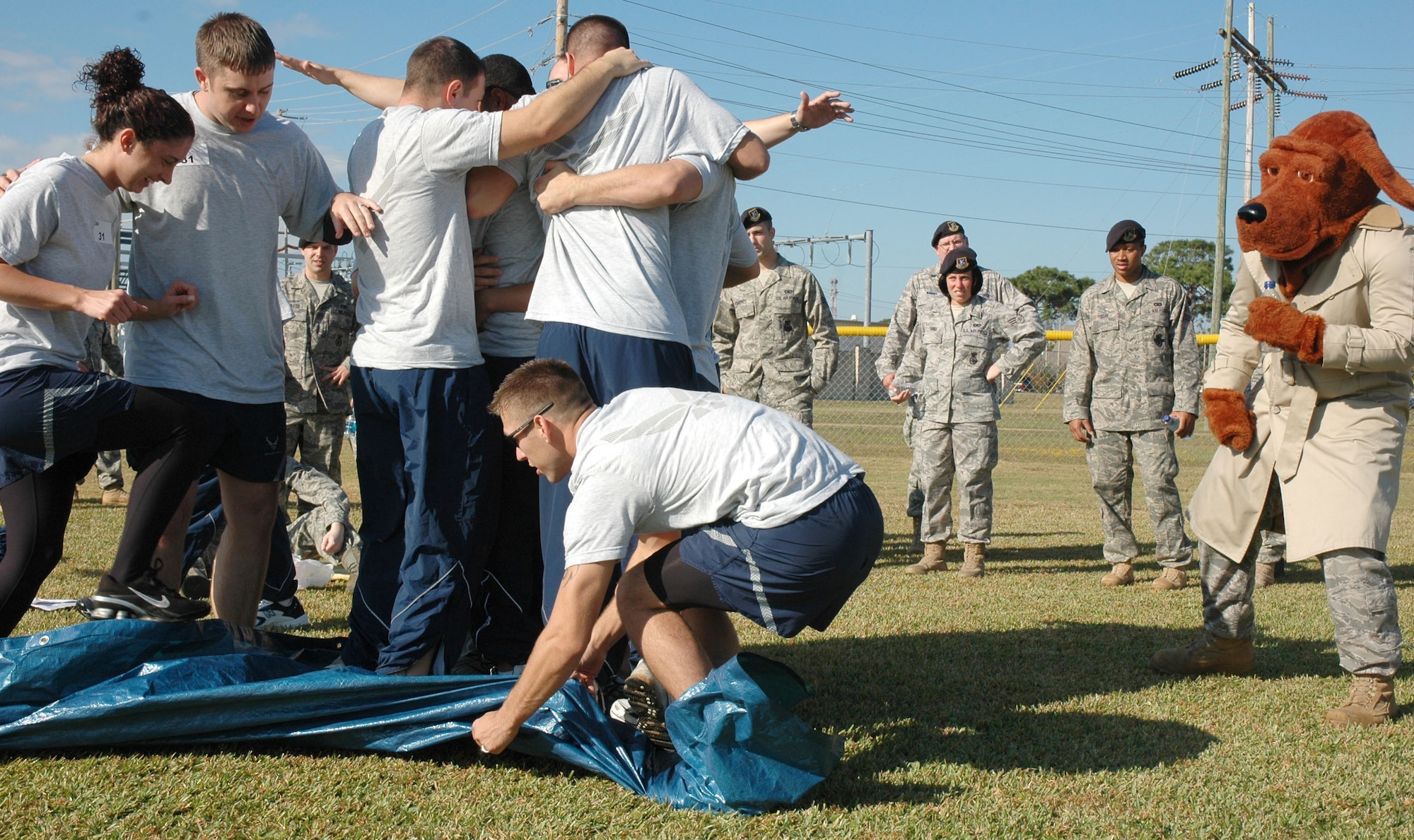EGLIN AIR FORCE BASE, Fla. -- Airmen from the 96th Security Forces Squadron team perform the the Magin Carpet challenge while McGruff the Crime Dog cheers them on. Wingman Day is a day of teambuilding exercises and other events aimed at fostering the Wingman concept of looking out for fellow Airmen. (U.S. Air Force photo/Staff Sgt. Stacia Zachary)