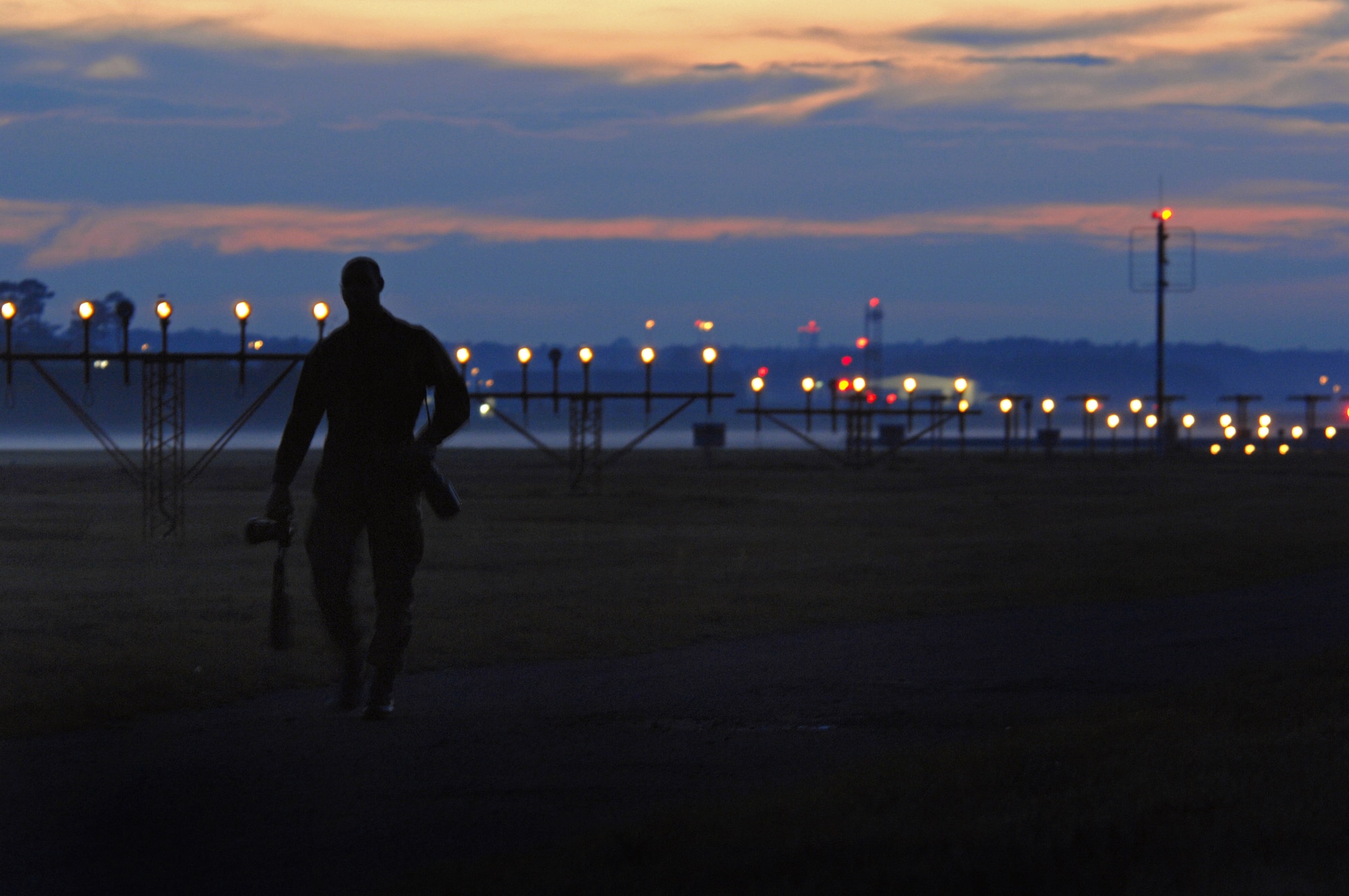 Airman 1st Class Kenny Holston walks off the flightline with his cameras after an evening of documenting aircraft operations Nov. 3 at Ramstein Air Base, Germany. Airman Holston is a 435th Air Base Wing photojournalist. (U.S. Air Force photo/Airman 1st Class Tony R. Ritter) 