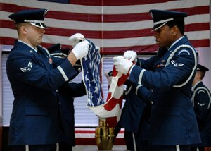 Senior Airman Nicholas Sansone and Airman 1st Class Derrick Gonzales along with other members of the honor guard fold a flag during a mock cremation ceremony after the ribbon cutting for their new training facility in Hunley Park Nov. 5. The honor guard relocated to a renovated building in Hunley Park to provide a better training environment. Airman Sansone is with the 437th Aerial Port Squadron and Airman Gonzales is with the 437th Maintenance Squadron.(U.S. Air Force photo/ Airman 1st Class Katie Gieratz)