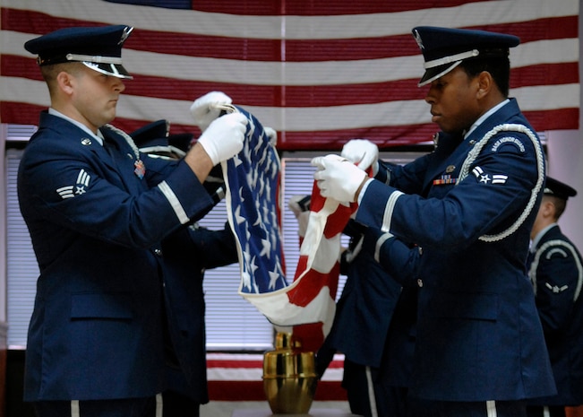 Senior Airman Nicholas Sansone and Airman 1st Class Derrick Gonzales along with other members of the honor guard fold a flag during a mock cremation ceremony after the ribbon cutting for their new training facility in Hunley Park Nov. 5. The honor guard relocated to a renovated building in Hunley Park to provide a better training environment. Airman Sansone is with the 437th Aerial Port Squadron and Airman Gonzales is with the 437th Maintenance Squadron.(U.S. Air Force photo/ Airman 1st Class Katie Gieratz)