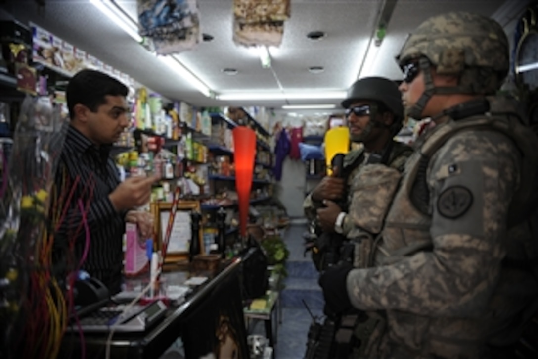 U.S. Army 1st Lt. John Nimmons (right), of 3rd Squadron, 3rd Armored Cavalry Regiment, and Iraqi army 2nd Lt. Ammar Hassin speak to a store owner during a joint operation patrol in Al Muhandiseen, Iraq, on Oct. 30, 2008.  