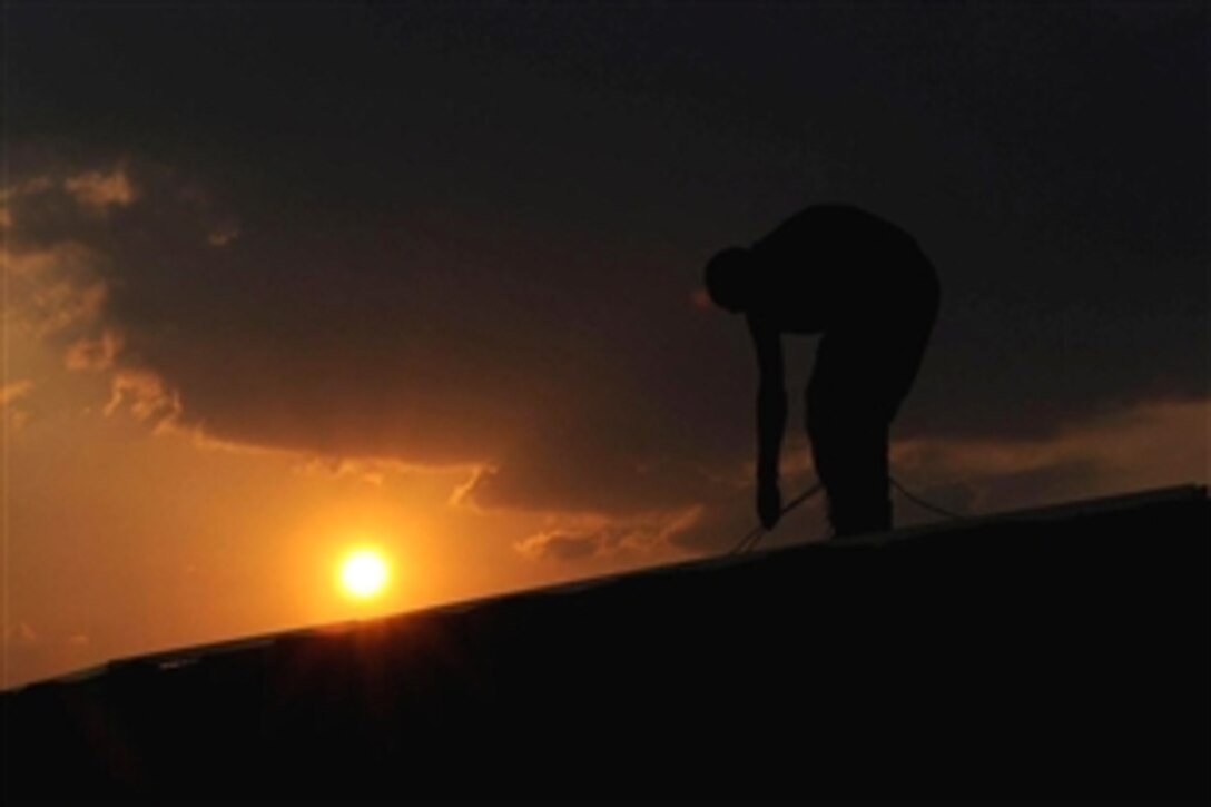 A British soldier lays cables on top of a protective wall during the evening hours at the Basra Operations Center, Basra, Iraq, Nov. 1, 2008. 