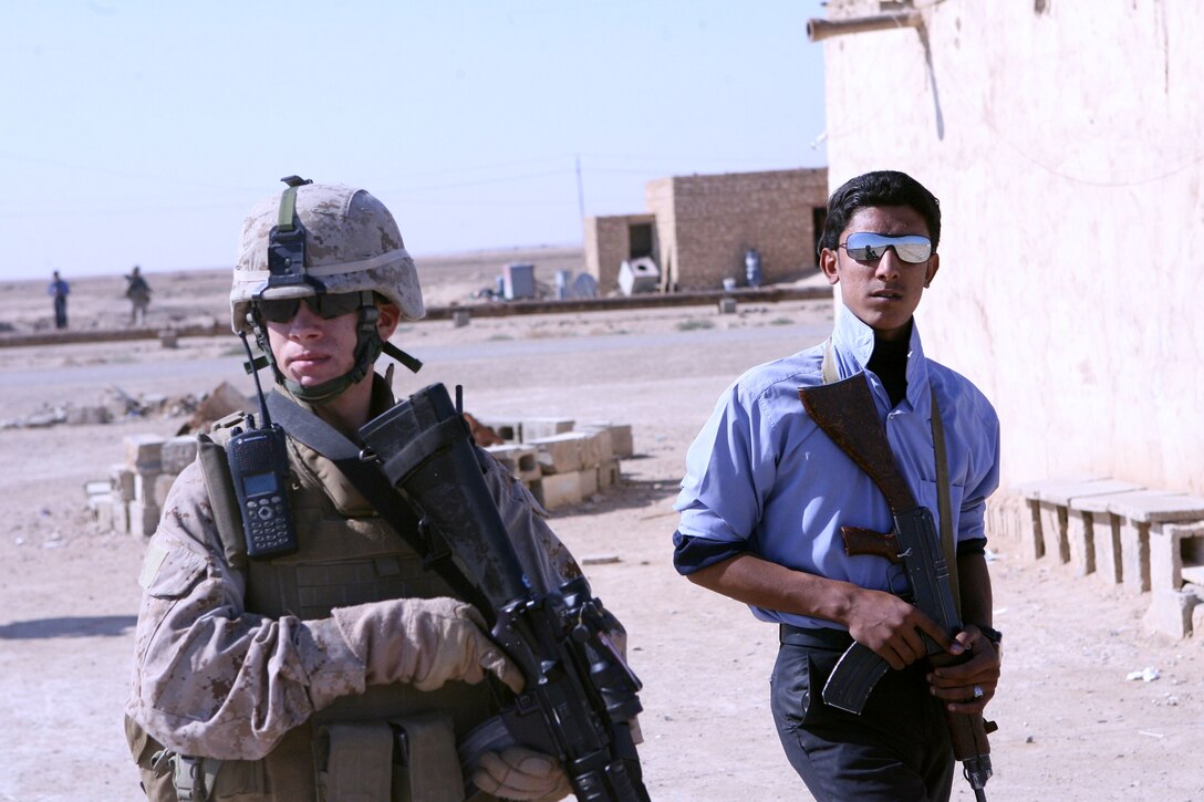 A Marine with Company E, 2nd Battalion, 9th Marine Regiment, Regimental Combat Team 1, walks side-by-side with an Iraqi Policeman on a partnered patrol near Ramadi, Iraq, Nov. 6. Company E Marines live on the same forward operating base as a unit of IPs, working and interacting with them on a daily basis.