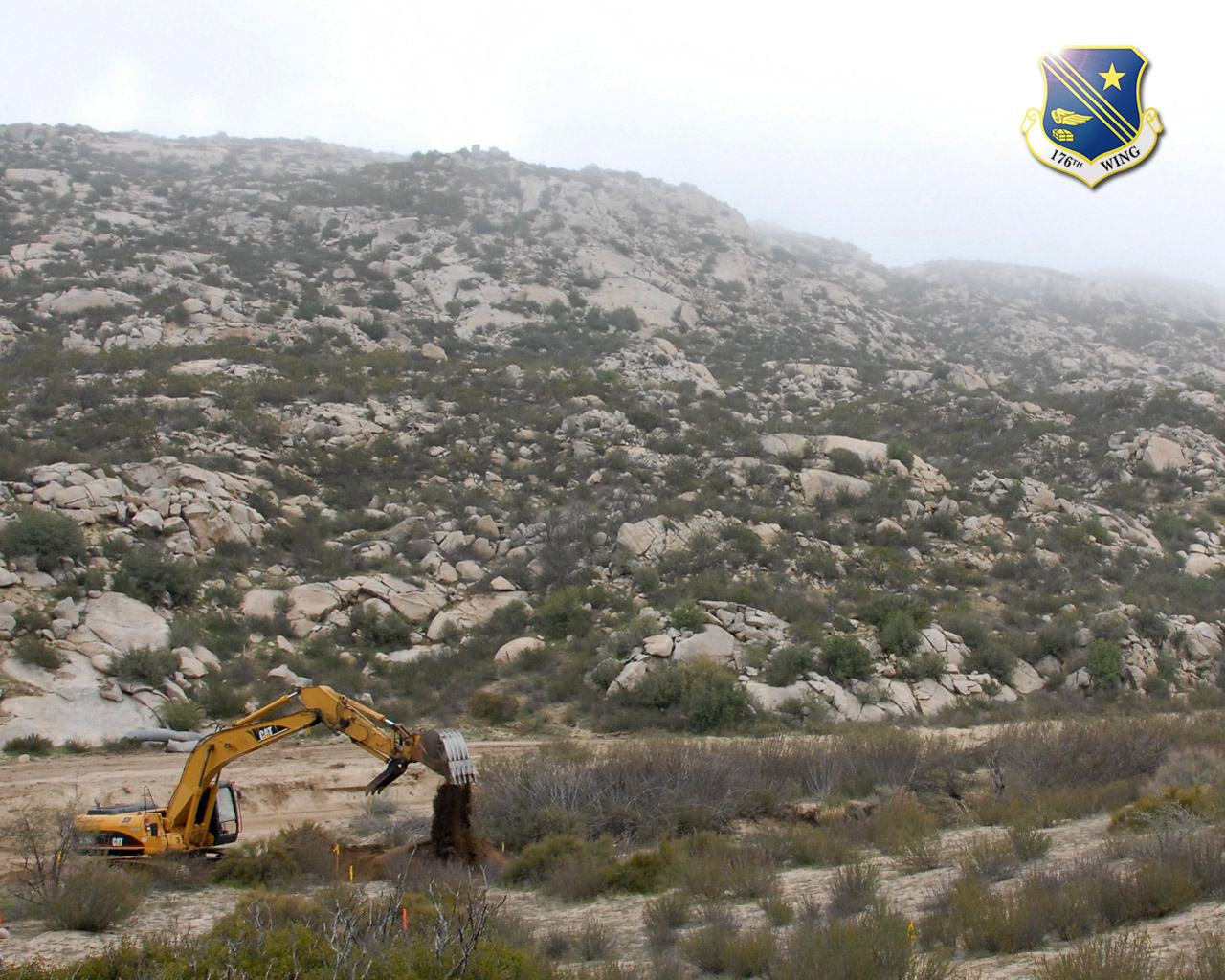 An excavator operated by a member of the 176th Wing's Civil Engineer Squadron improves a road used by the U.S. Border Patrol in the remote hills east of San Diego along the U.S.-Mexican border. Members of the 176 CES deployed to California for two weeks in 2008 as part of Operation Jump Start, a federal effort to help secure the border. Alaska Air National Guard photo by 2Lt John Callahan.