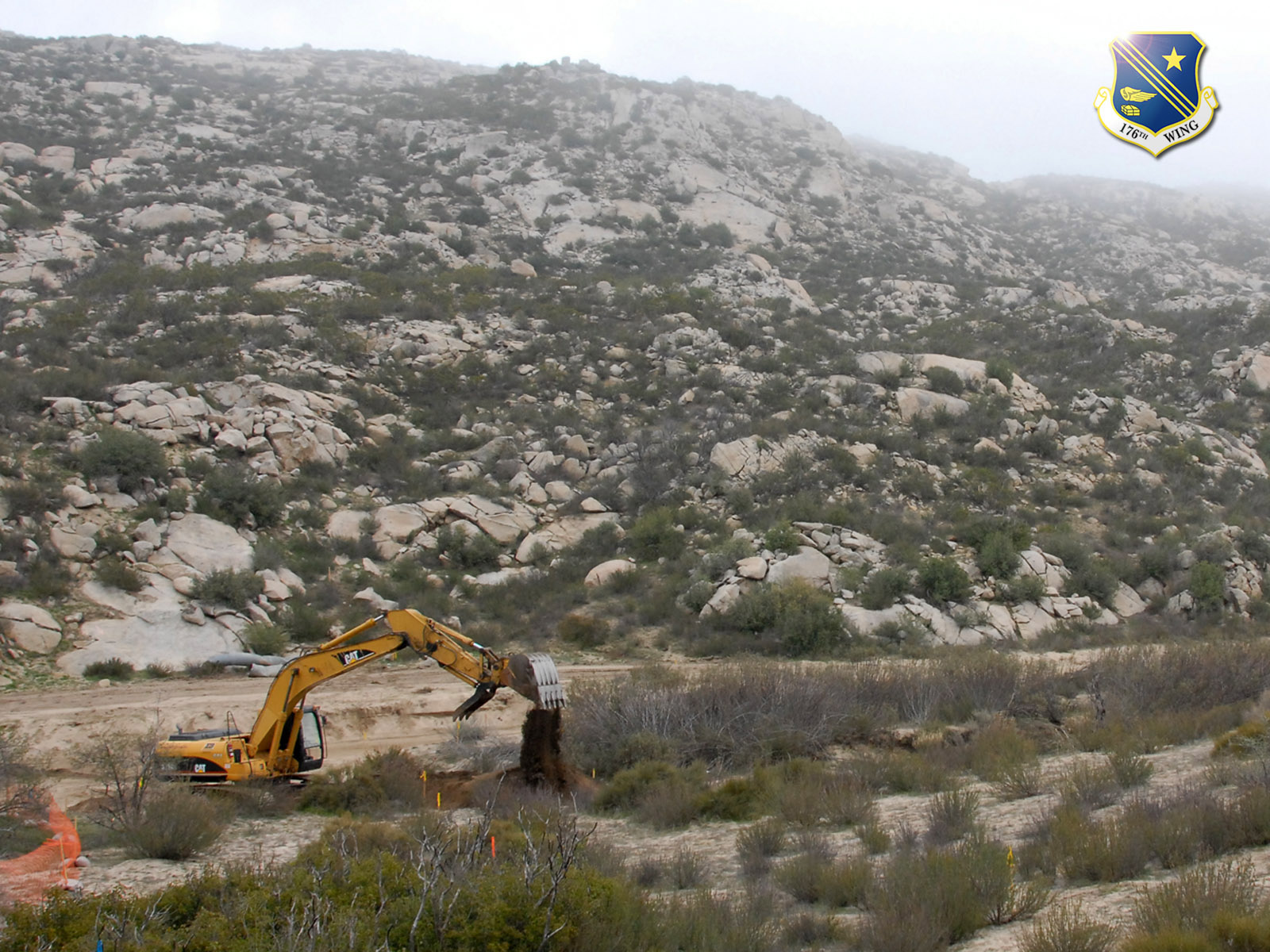An excavator operated by a member of the 176th Wing's Civil Engineer Squadron improves a road used by the U.S. Border Patrol in the remote hills east of San Diego along the U.S.-Mexican border. Members of the 176 CES deployed to California for two weeks in 2008 as part of Operation Jump Start, a federal effort to help secure the border. Alaska Air National Guard photo by 2Lt John Callahan.